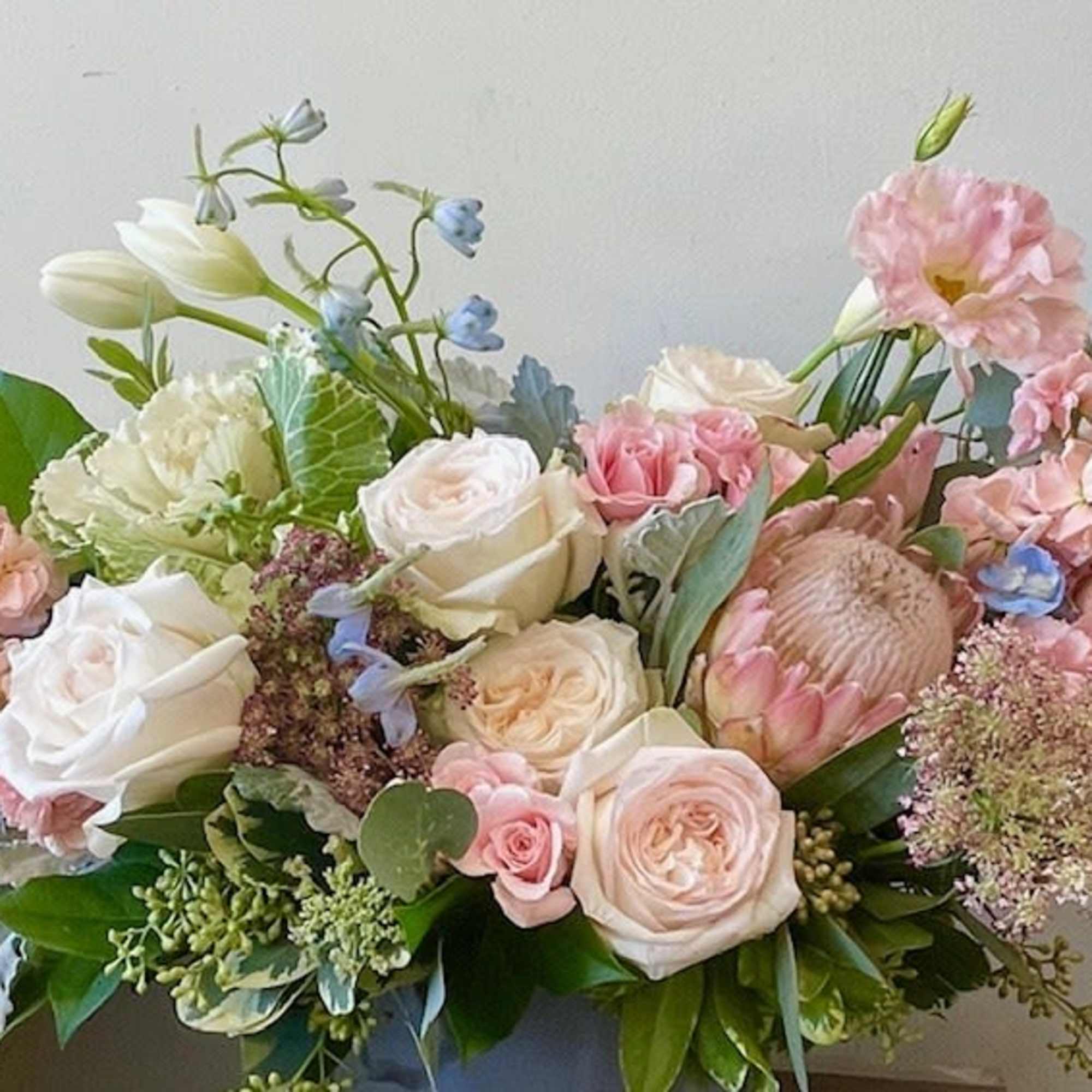 Pastel bouquet of roses, lisianthus, and blue accent flowers