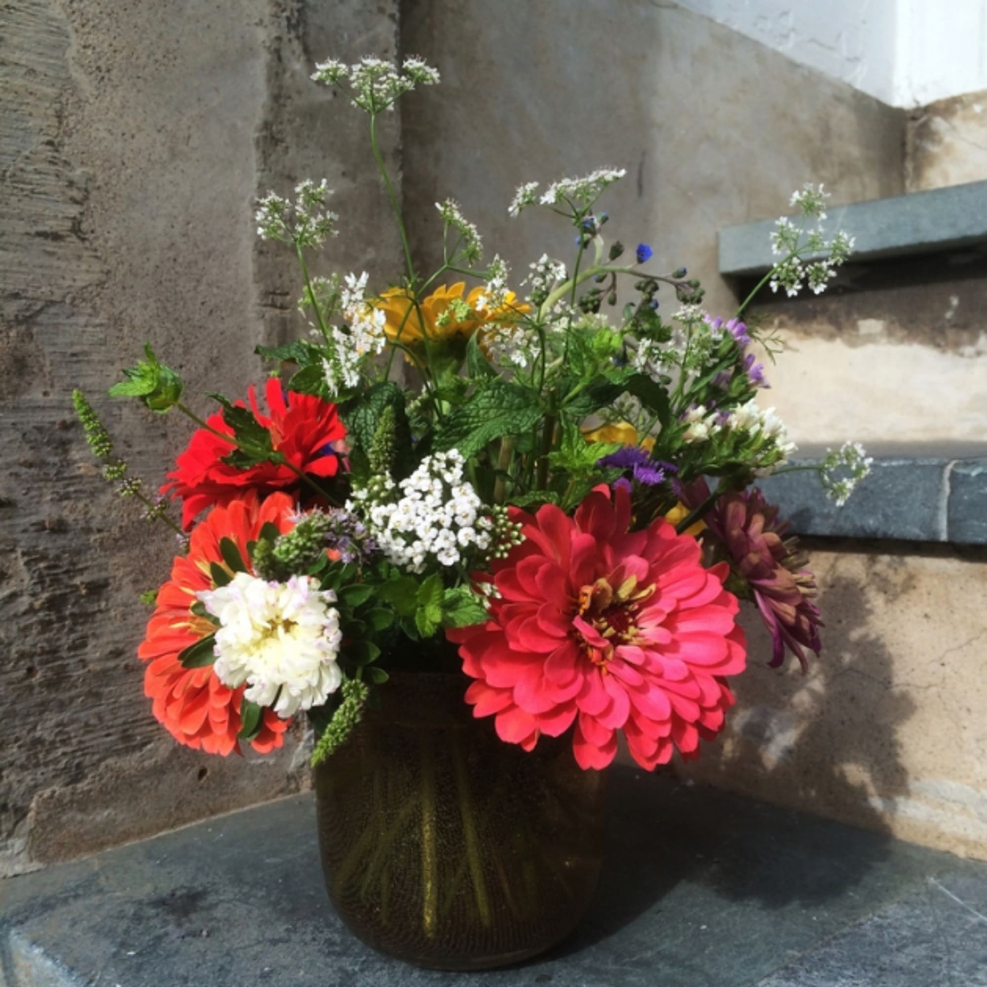 Mixed bouquet of bright flowers in a dark glass vase