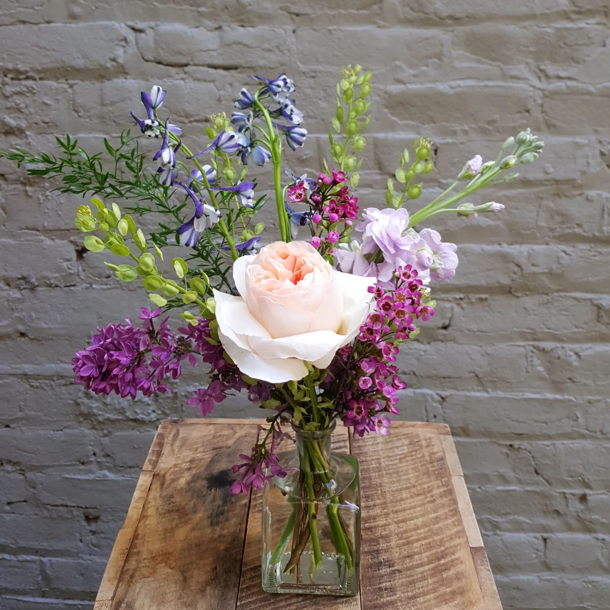 Mixed bouquet with a pale peach rose in a clear glass vase