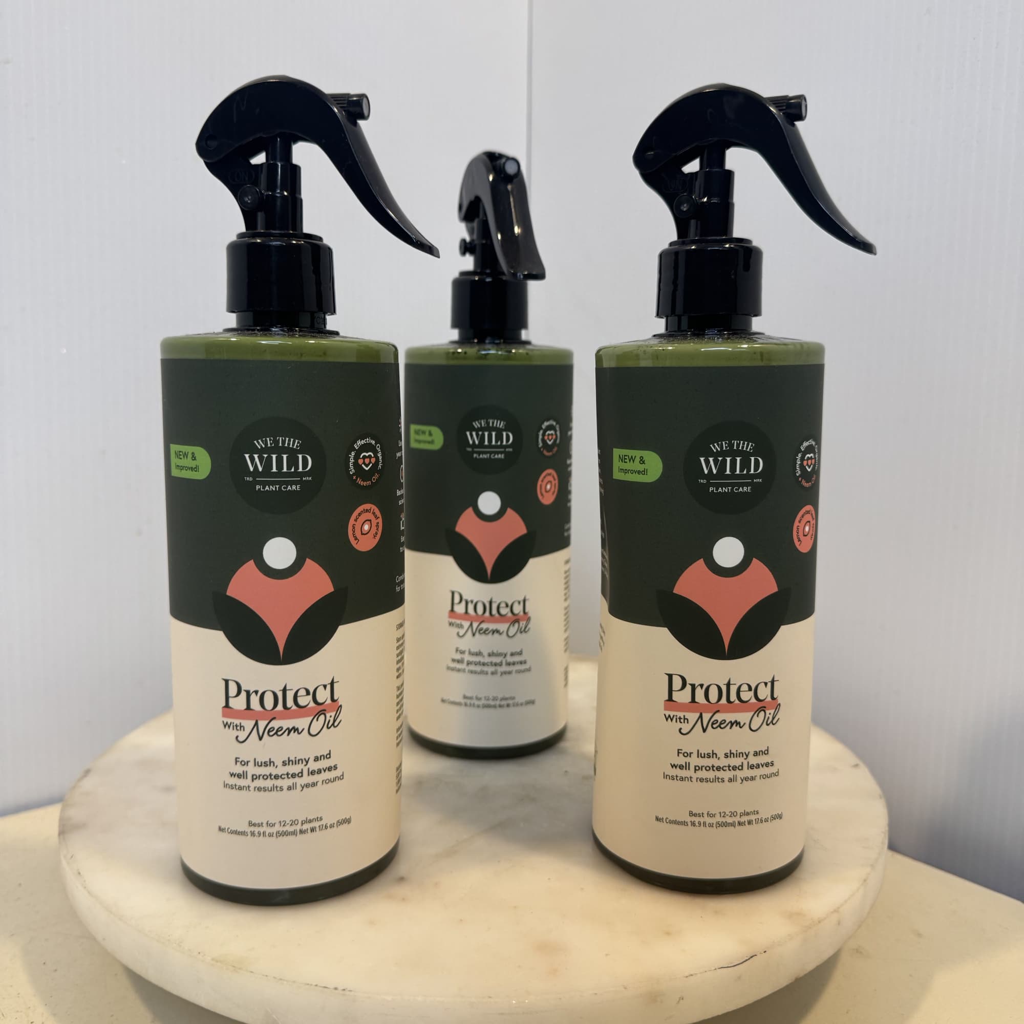 Three plant care spray bottles on a round marble stand