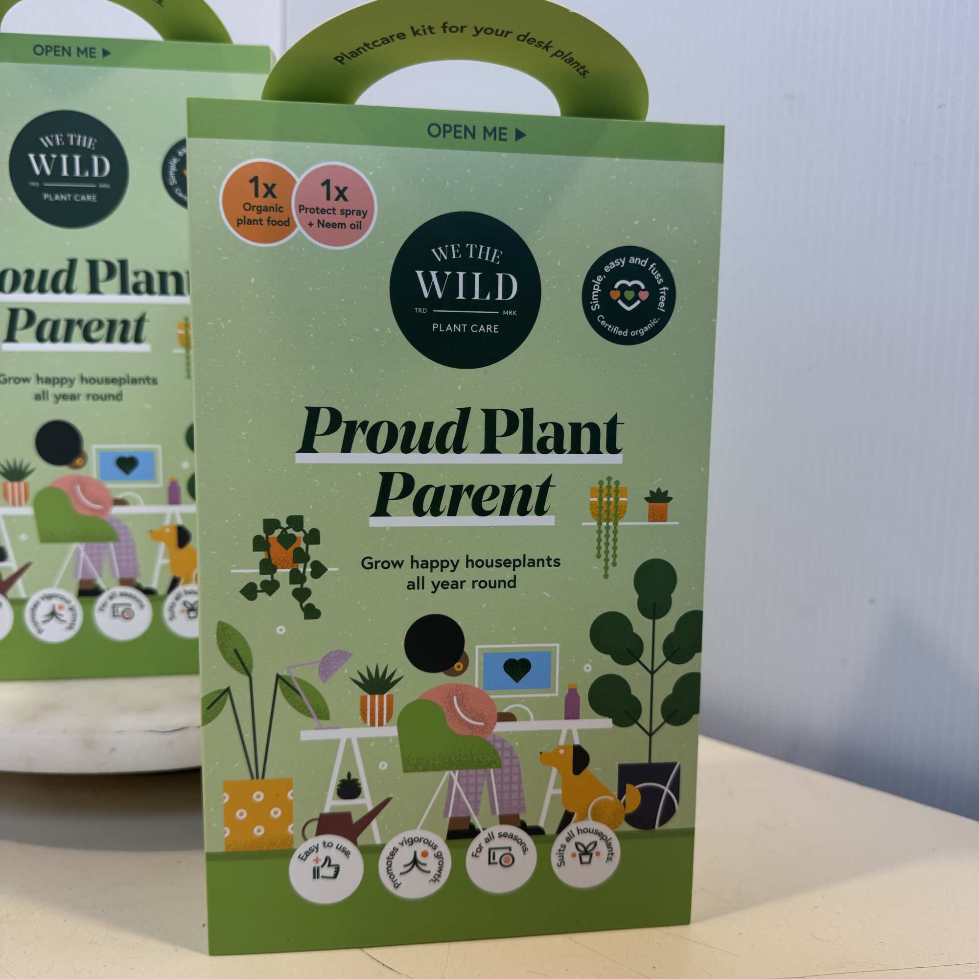 Two plant care gift boxes with green handles and illustrated houseplants