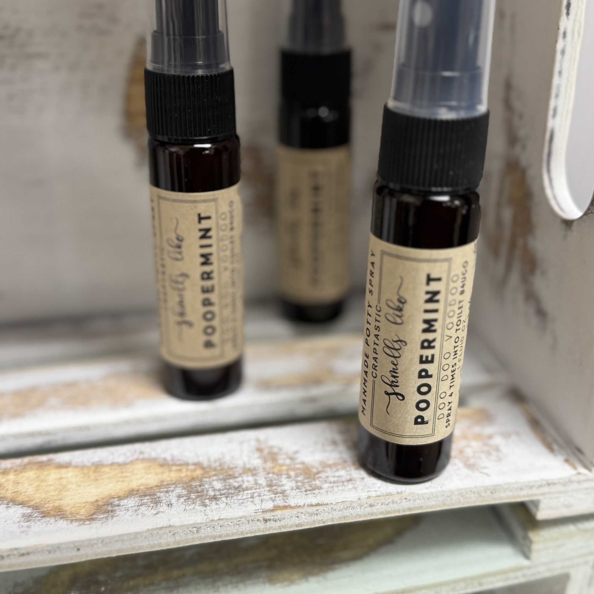 Three small spray bottles labeled peppermint sit on a shelf.