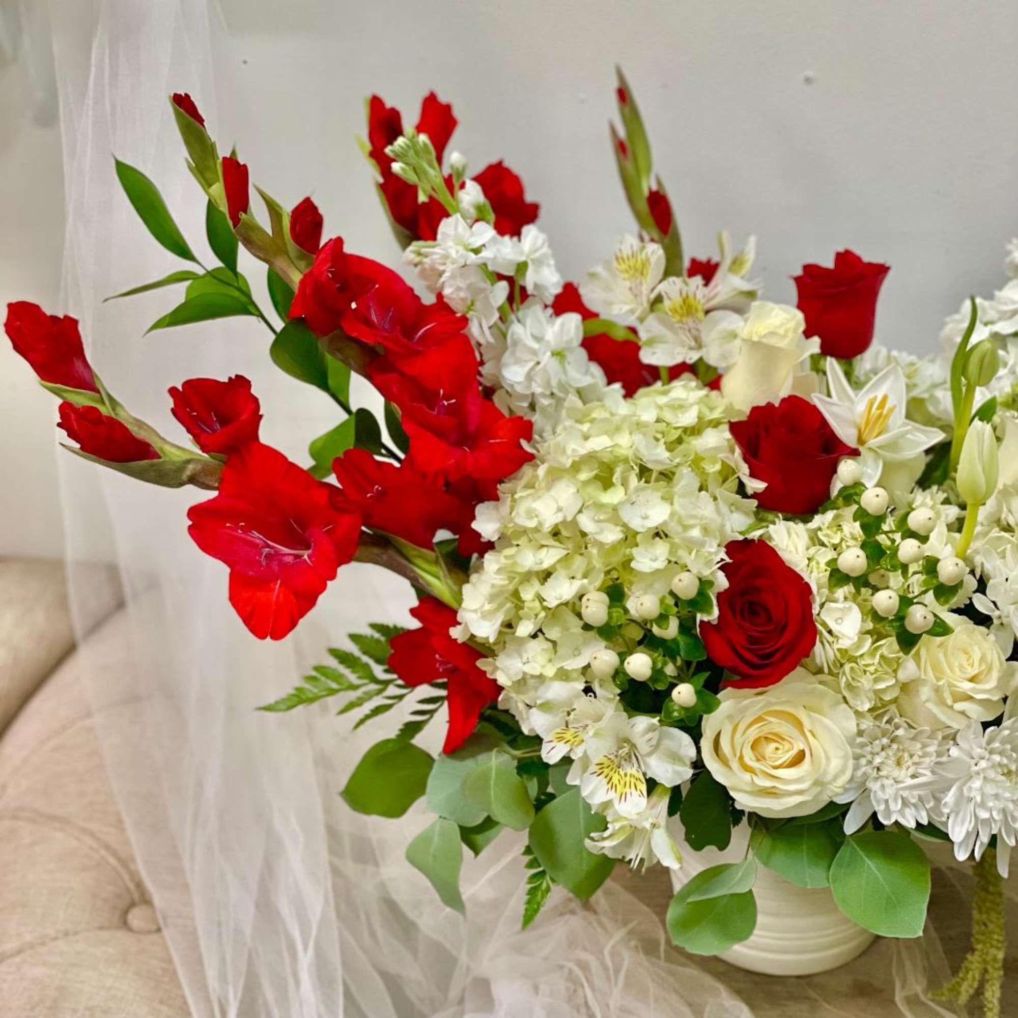 Red and white floral arrangement in a white vase