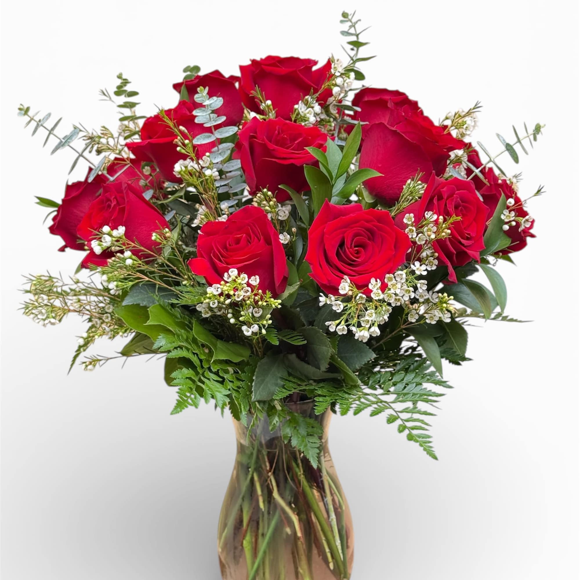 Red roses arranged in a glass vase with small white filler flowers