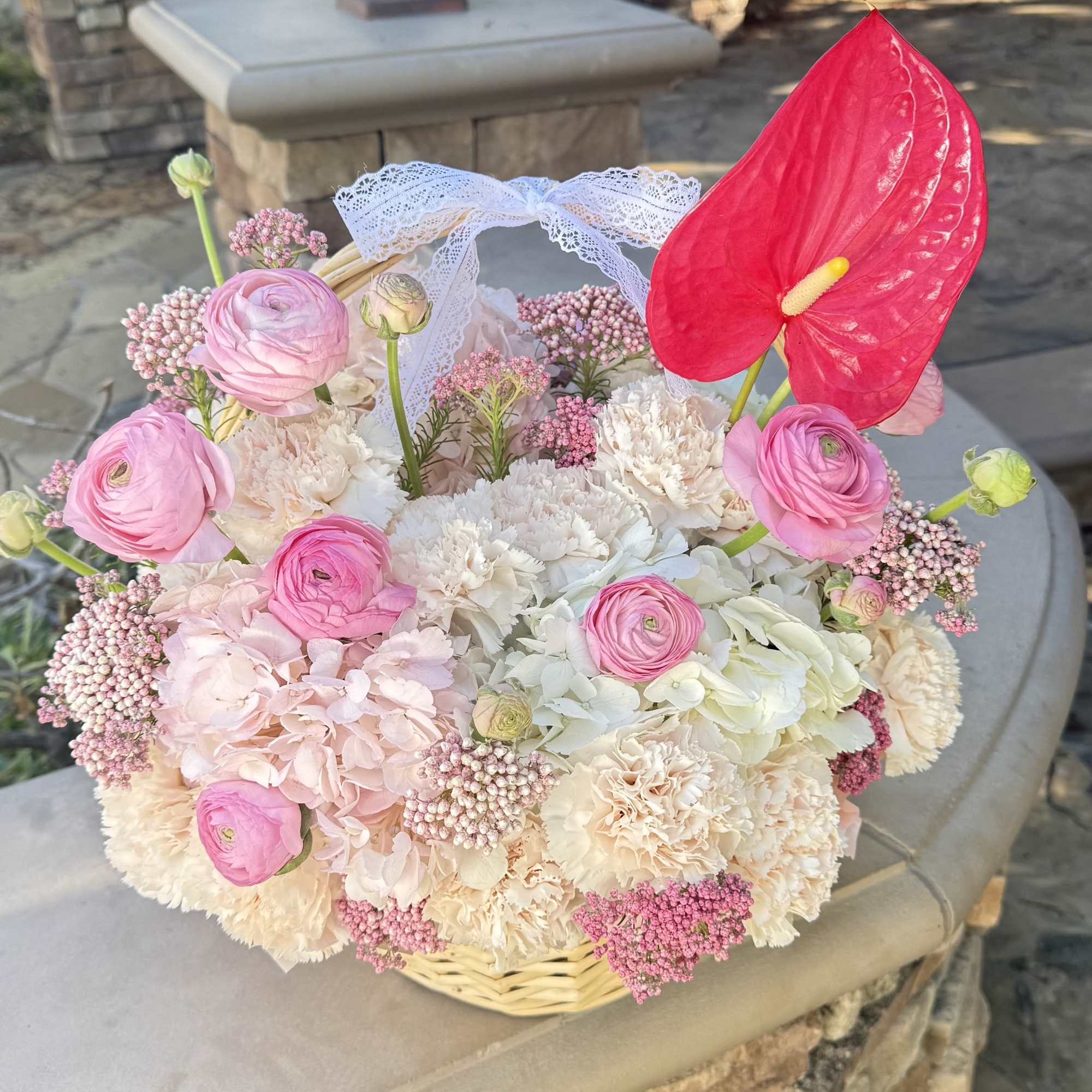 A delicate basket arrangement filled with soft pink and creamy white flowers