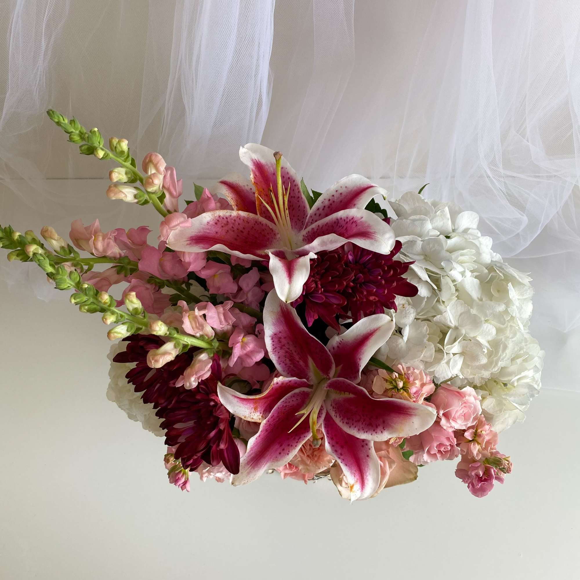 Pink lilies and mixed blooms arranged with white hydrangea.