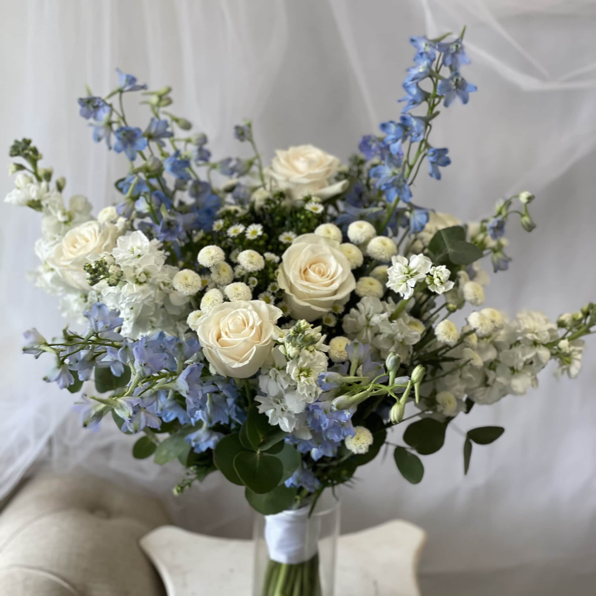 Blue and white bouquet of roses and delphinium in a glass vase