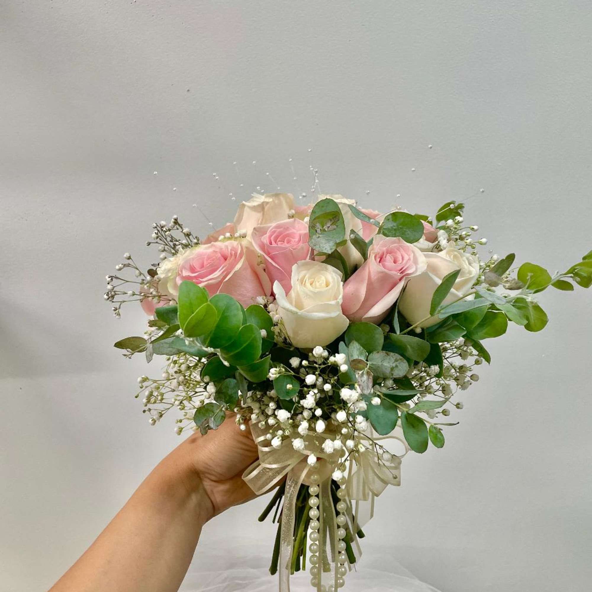 Handheld bouquet of pink and white roses with baby's breath