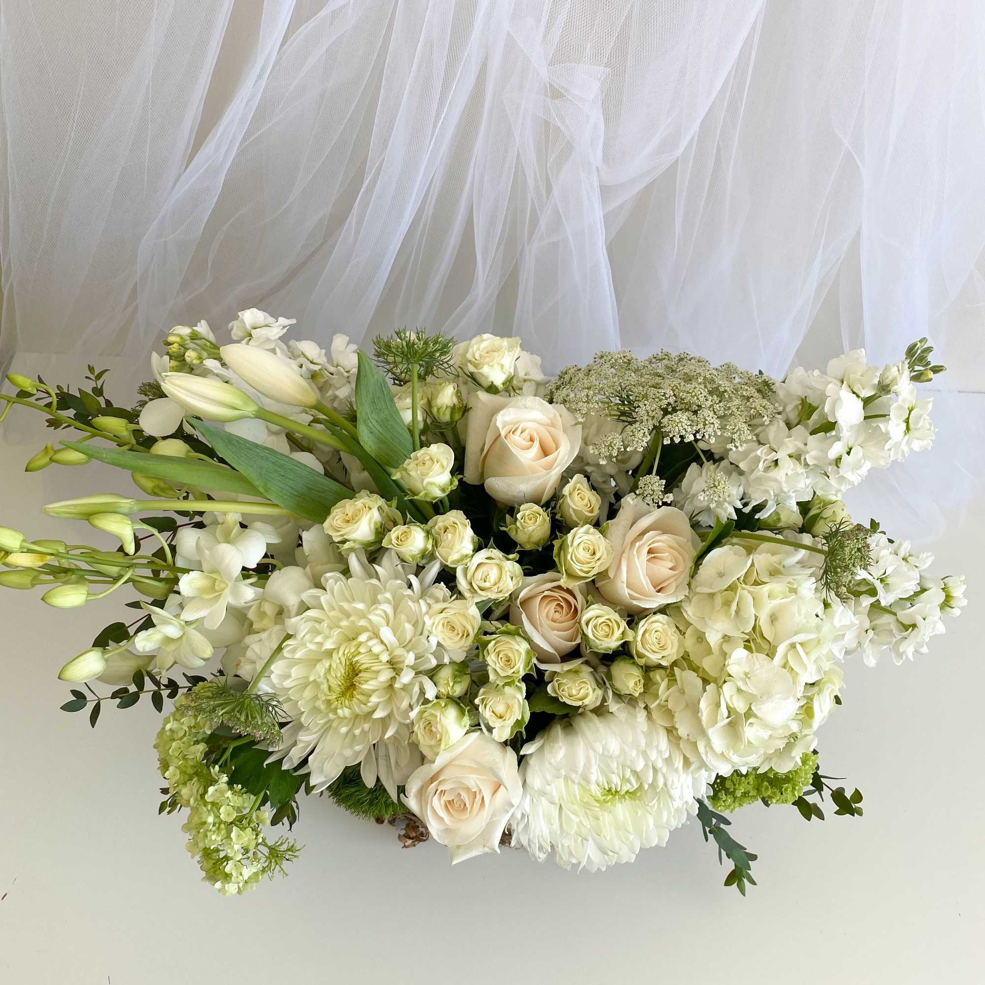 White and cream floral arrangement with roses, lilies, and chrysanthemums