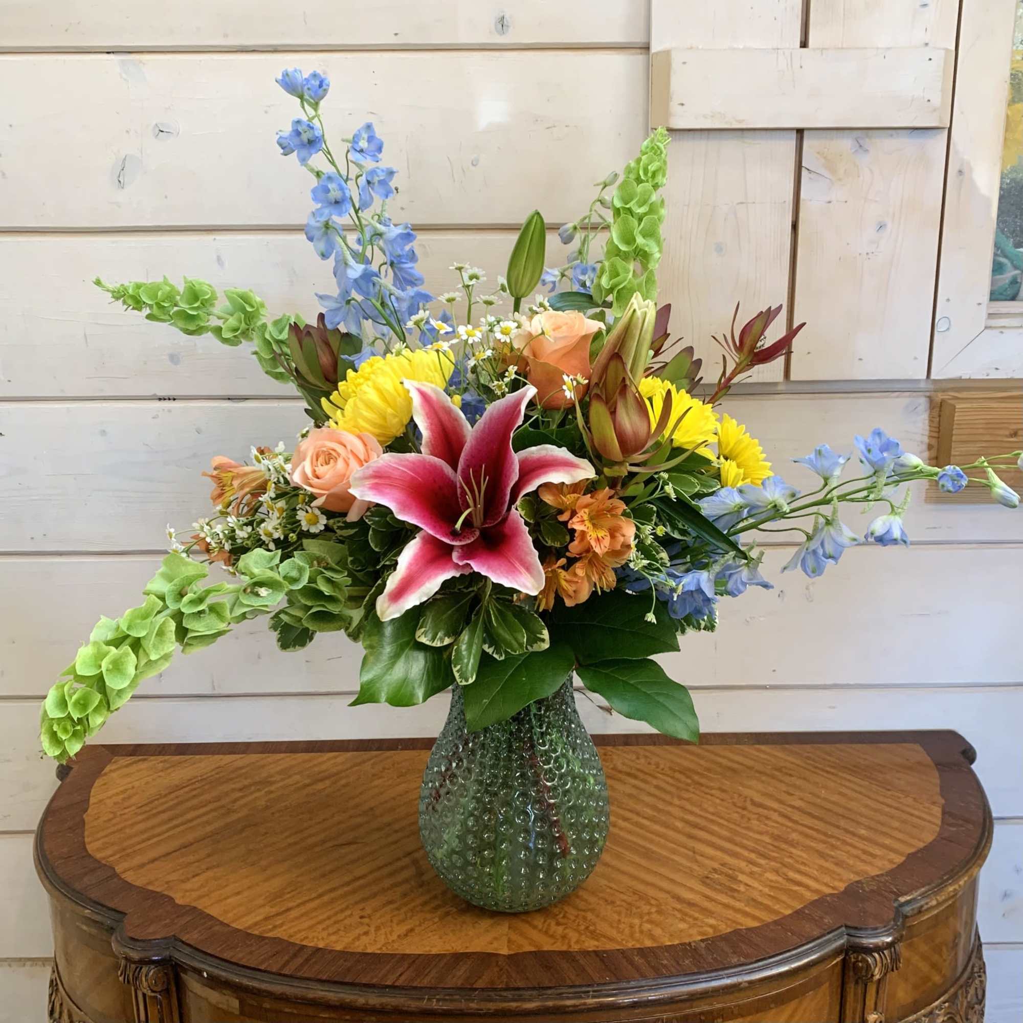 Apricot roses and stargazer lilies with pale blue delphinium, bells of Ireland