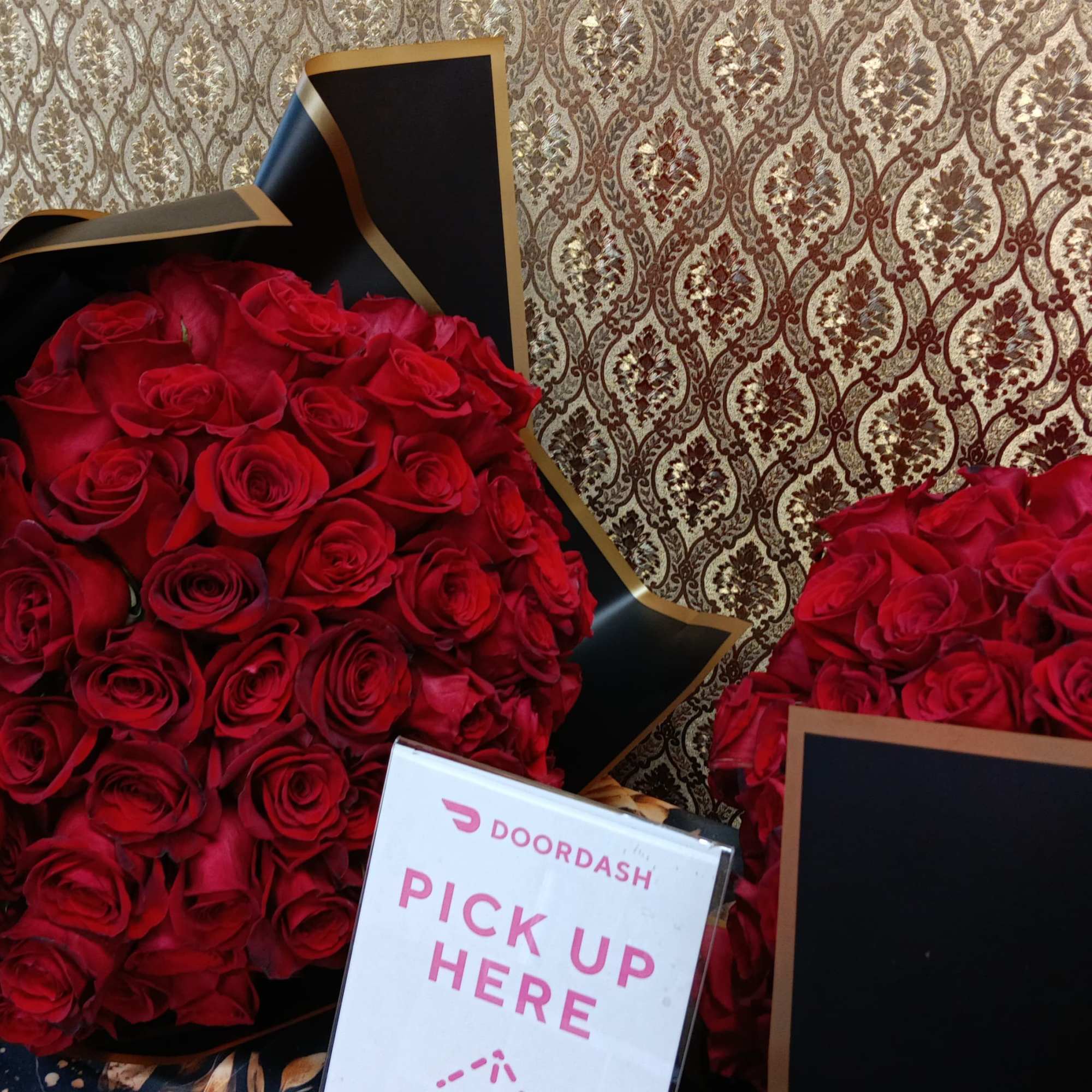 Two large bouquets of red roses in black wrapping with a pickup sign