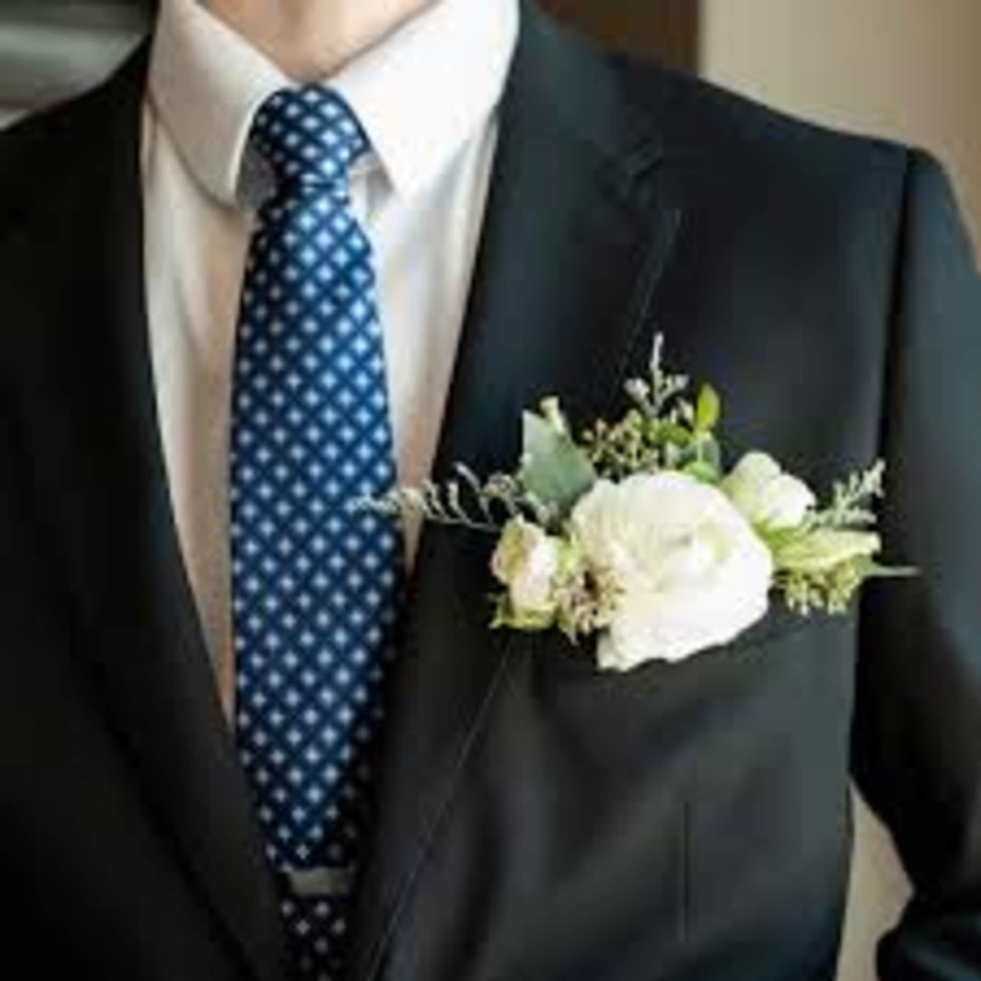 White boutonniere pinned to a dark suit jacket