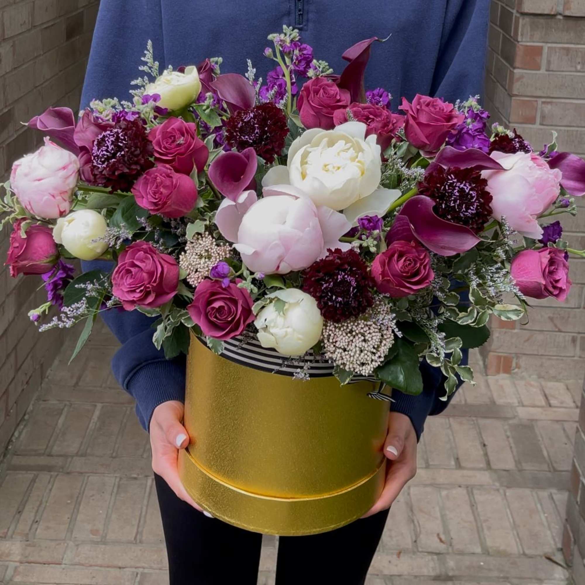 Large bouquet of pink and white flowers in a gold hatbox