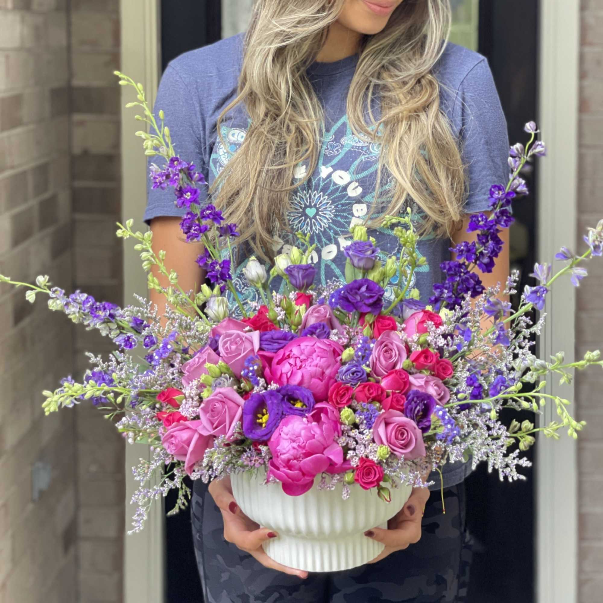 Large pink and purple flower arrangement in a white vase