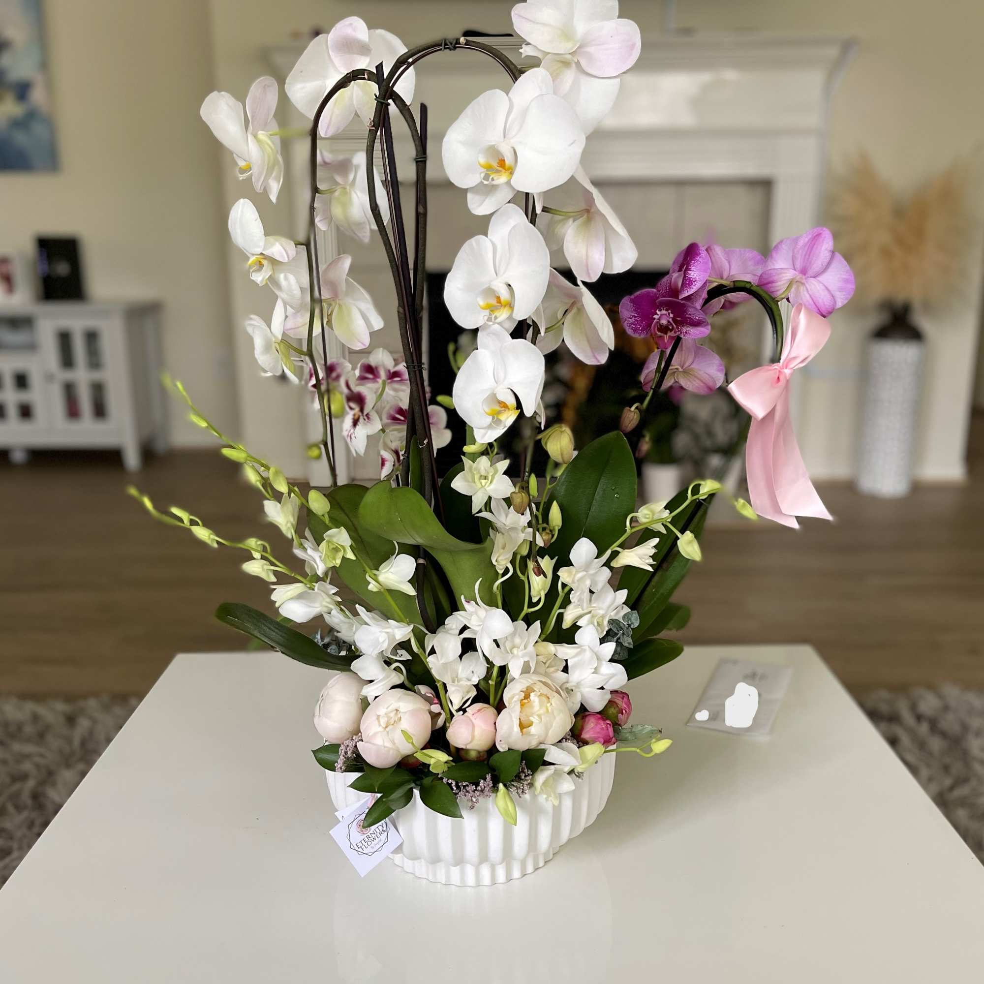 White and pink orchid arrangement in a white ceramic container