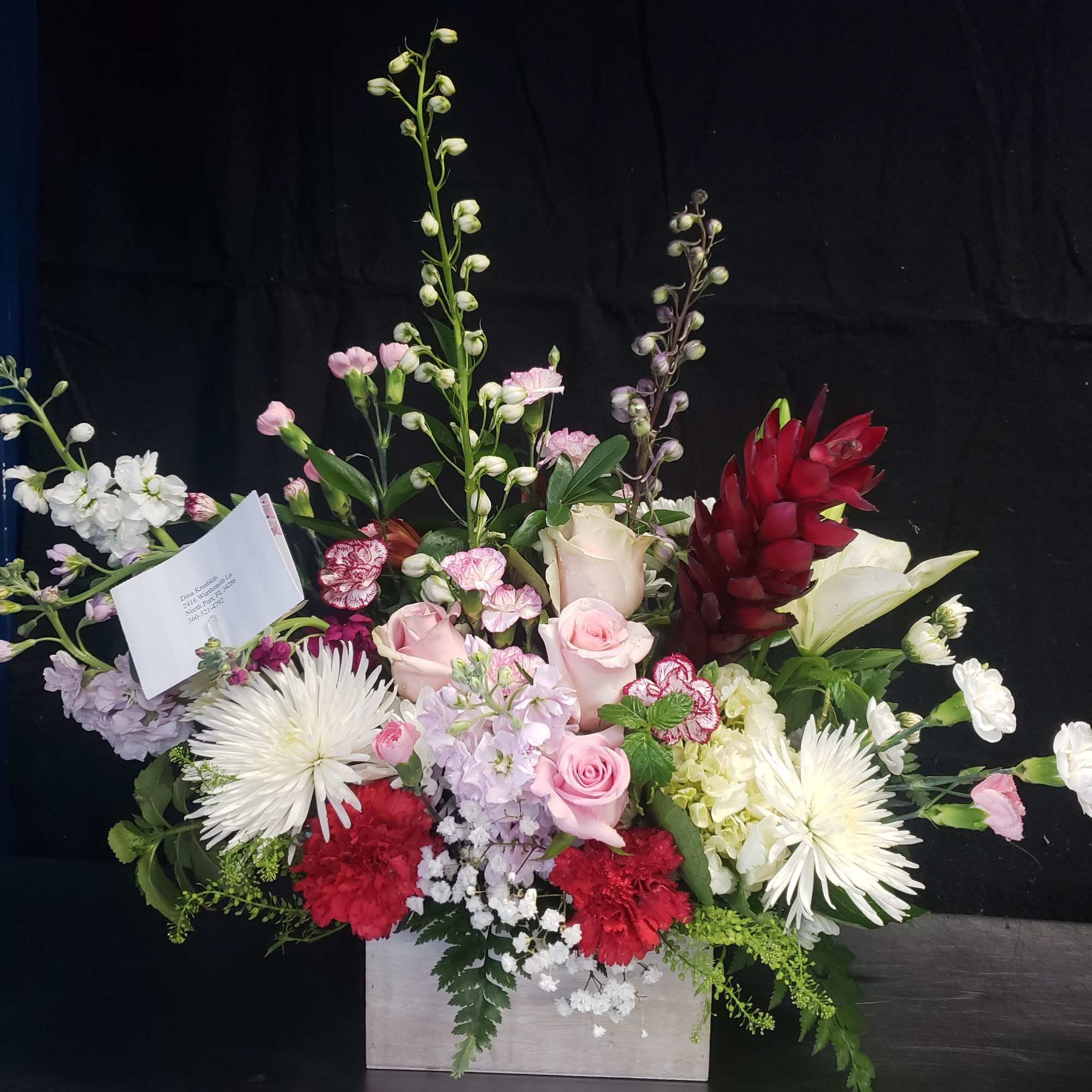 Pale pink roses and white lilies rise above a generous bed of