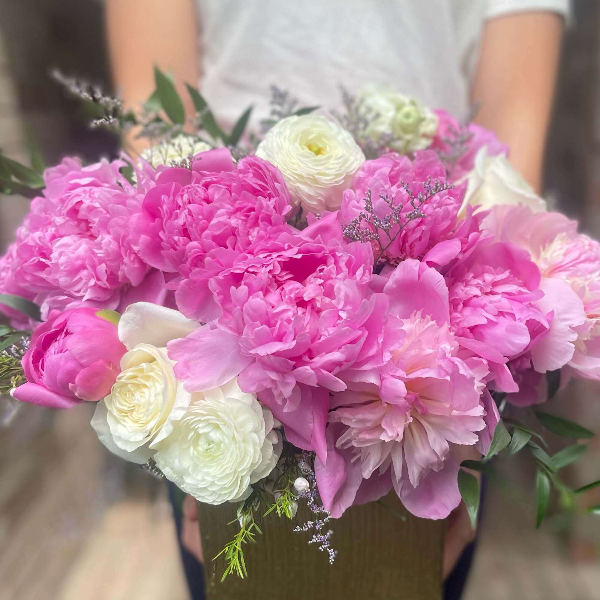 Large bouquet of pink and white flowers held in front of a person
