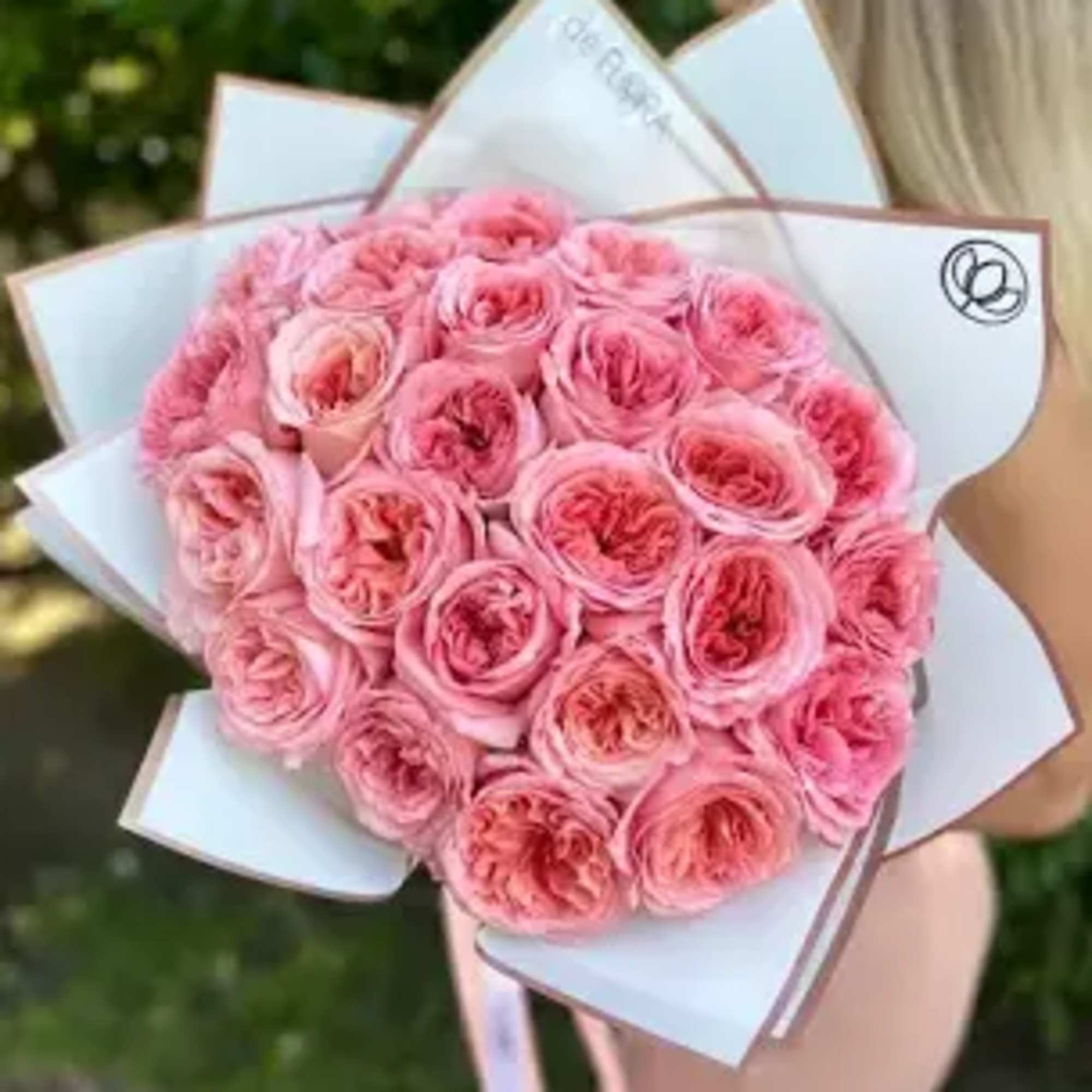 Round bouquet of pink roses wrapped in white paper