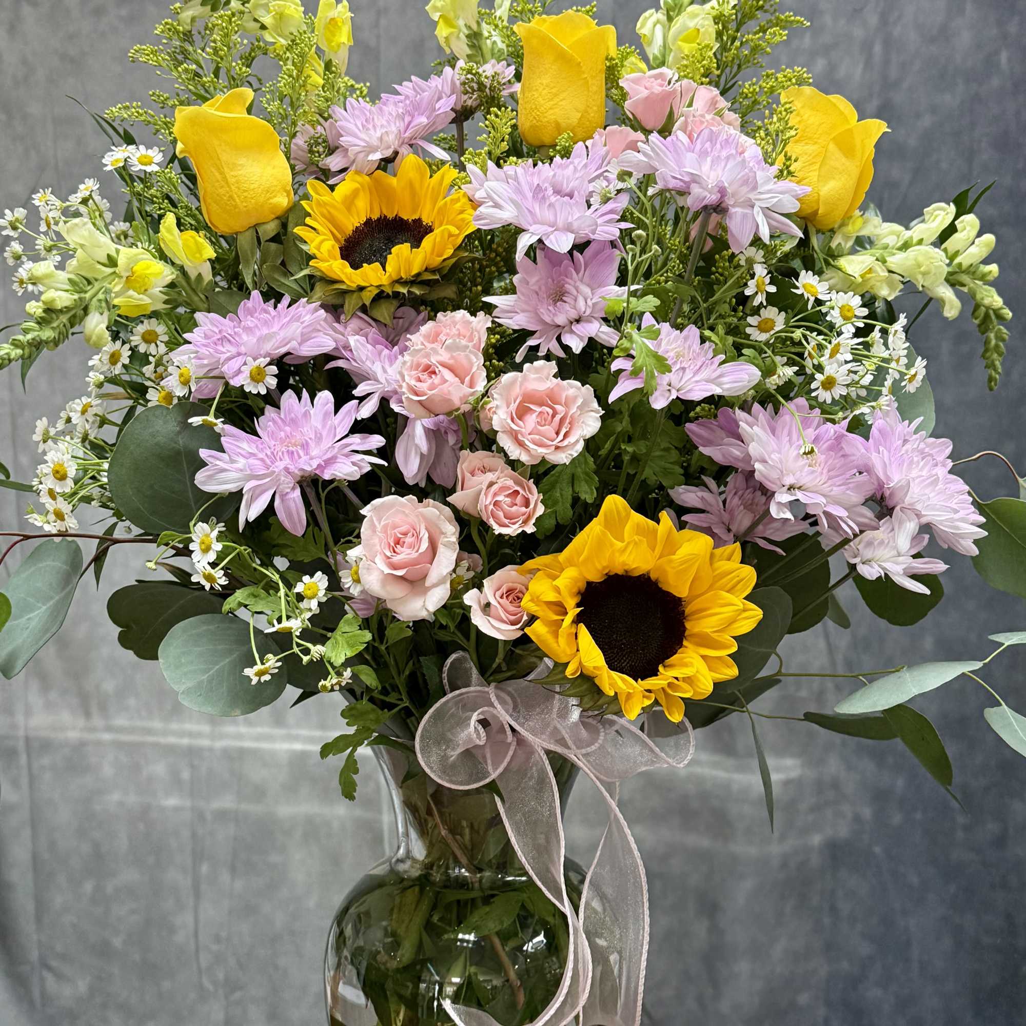 A radiant mix of golden sunflowers, sunny yellow roses, delicate pink spray