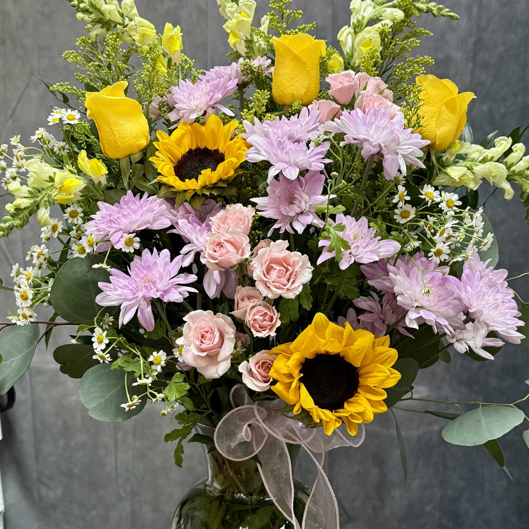 A radiant mix of golden sunflowers, sunny yellow roses, delicate pink spray