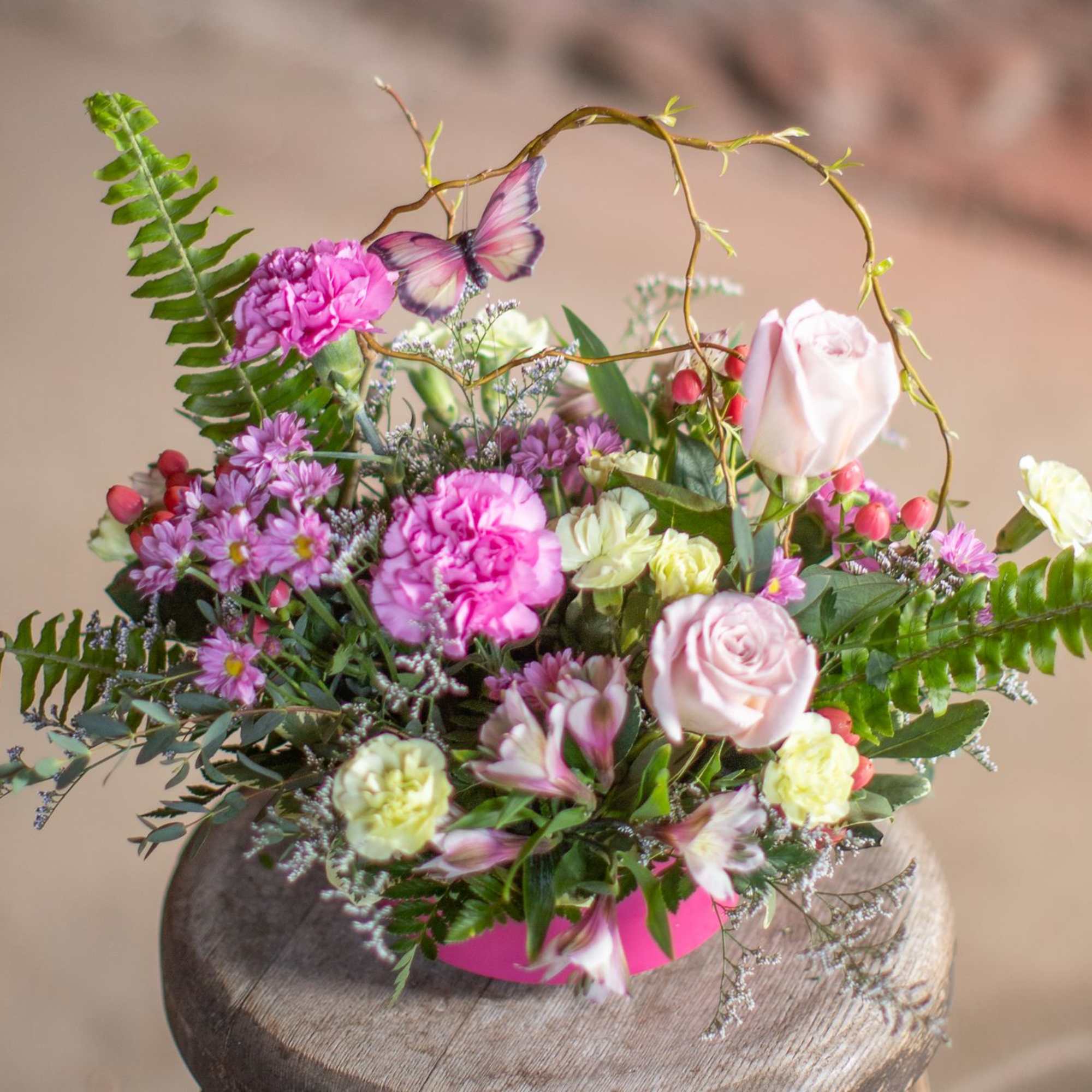 A butterfly dances through woven curly willow branches and festive seasonal blooms