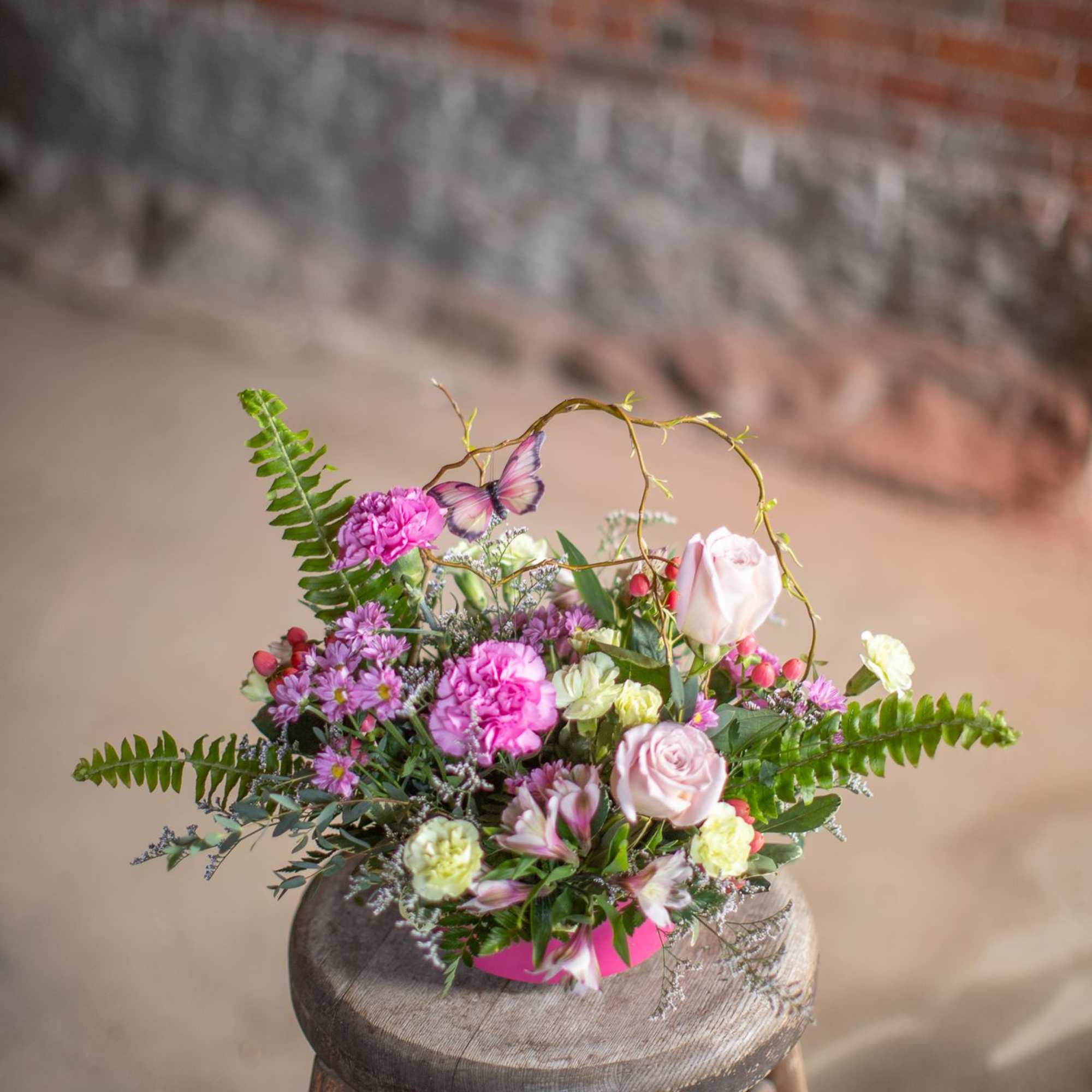 A butterfly dances through woven curly willow branches and festive seasonal blooms