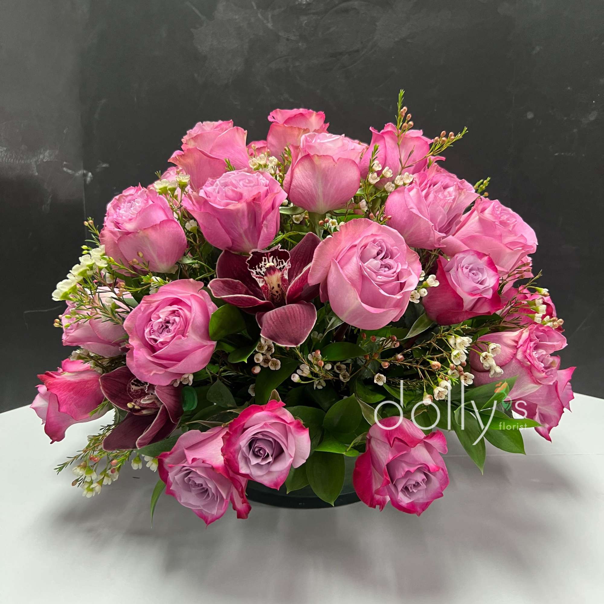 A lush dome of blush and hot-pink roses crowned with deep burgundy