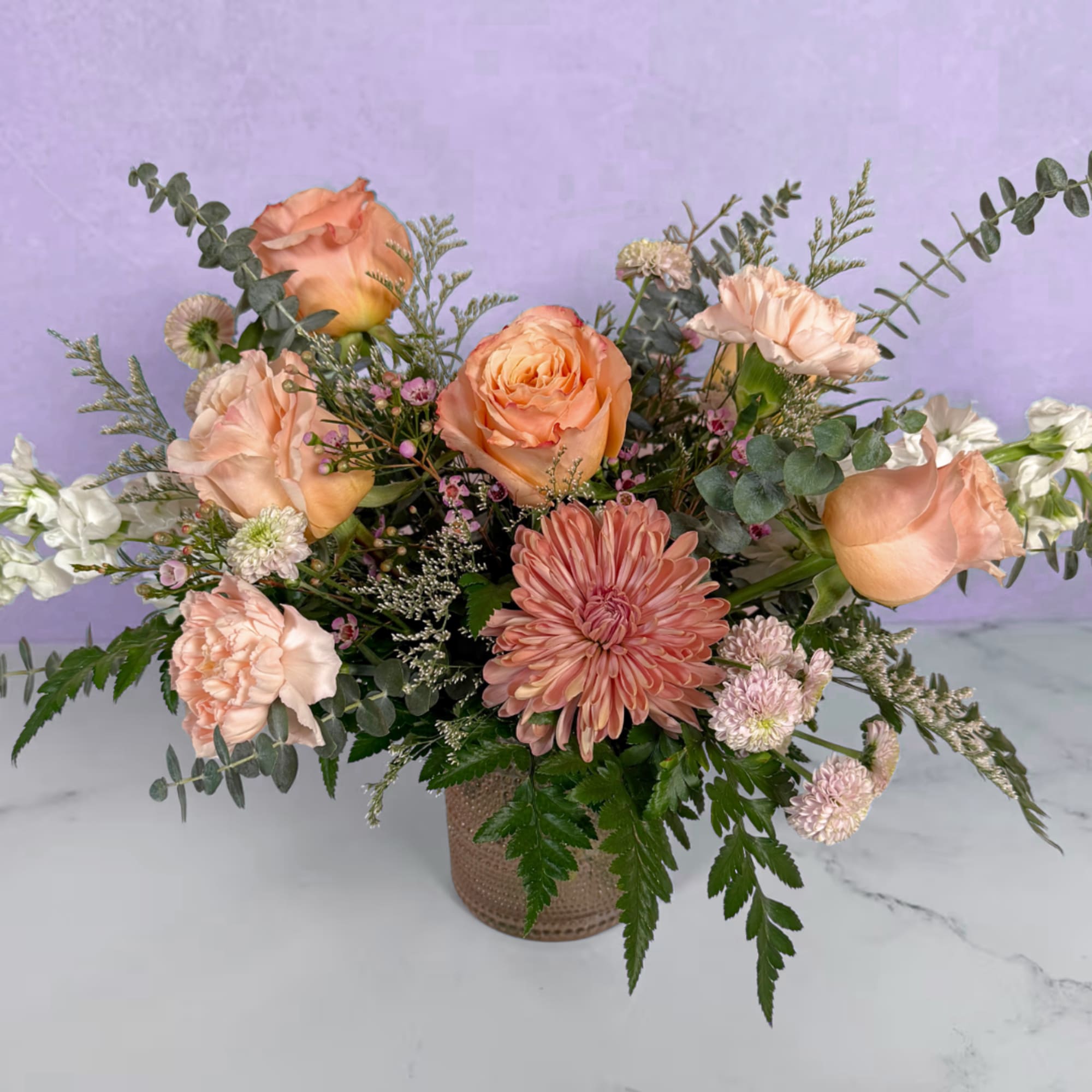Peach roses and a large pink chrysanthemum form the heart of this
