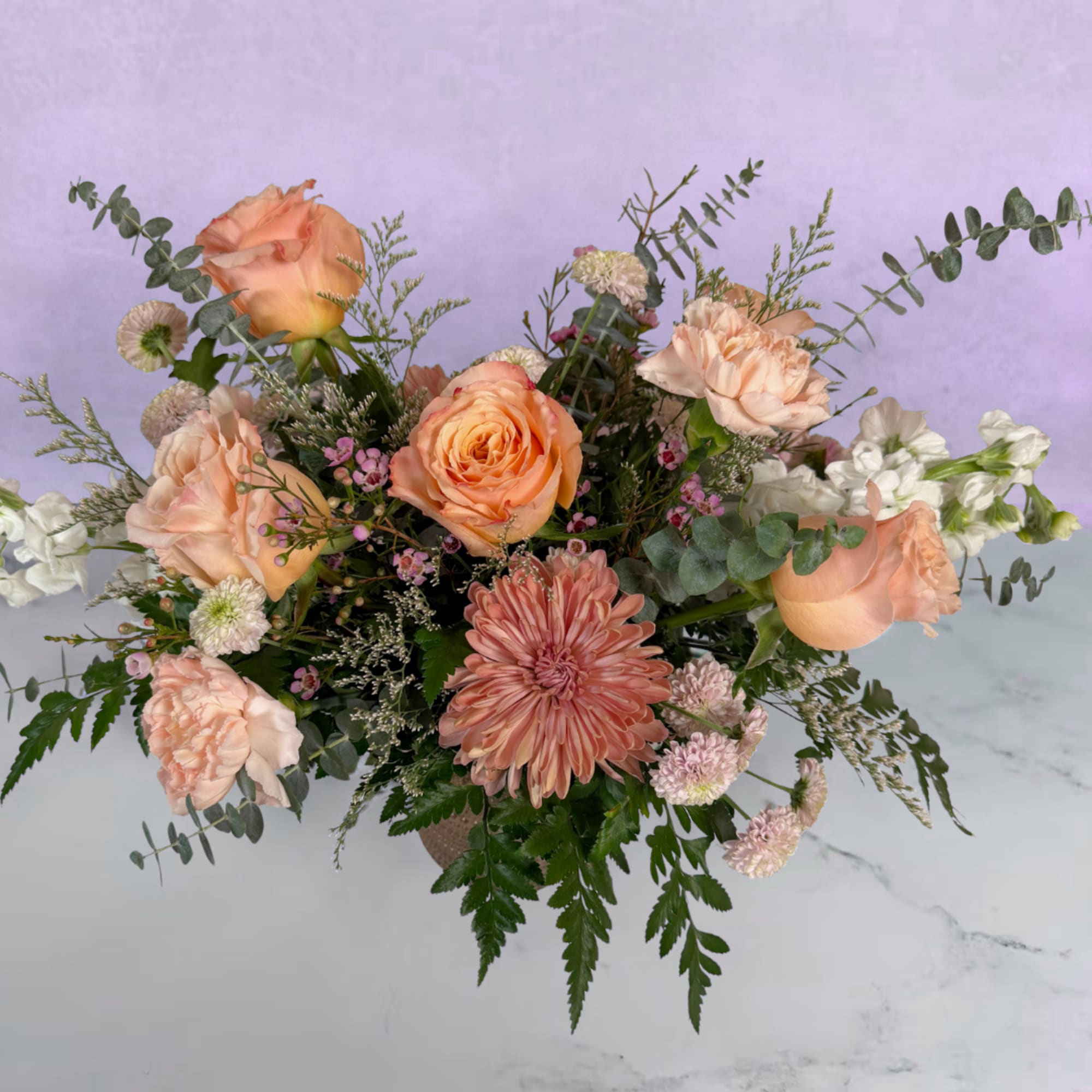Peach roses and a large pink chrysanthemum form the heart of this