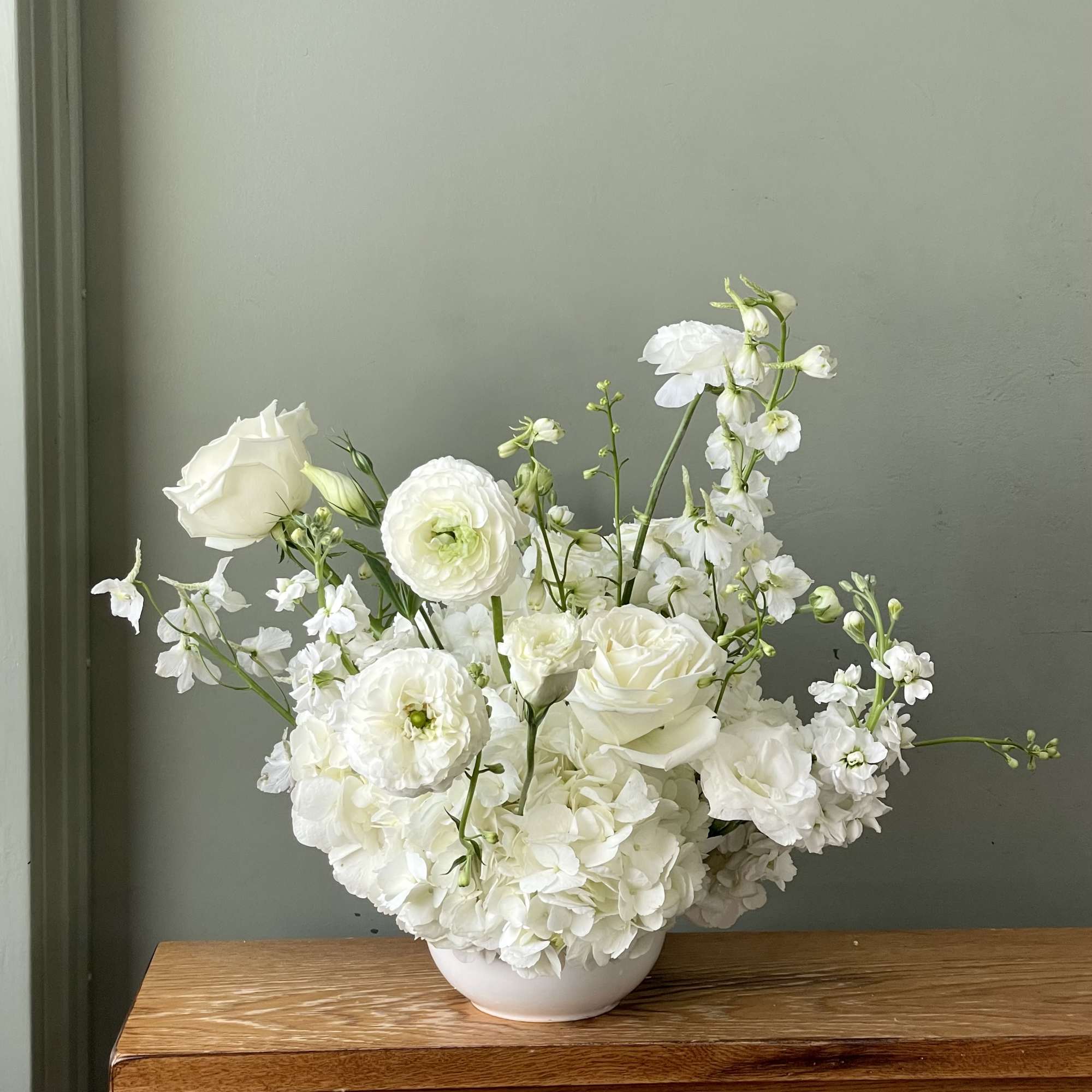 A lush garden of crisp white blooms, thoughtfully arranged with hydrangea, roses