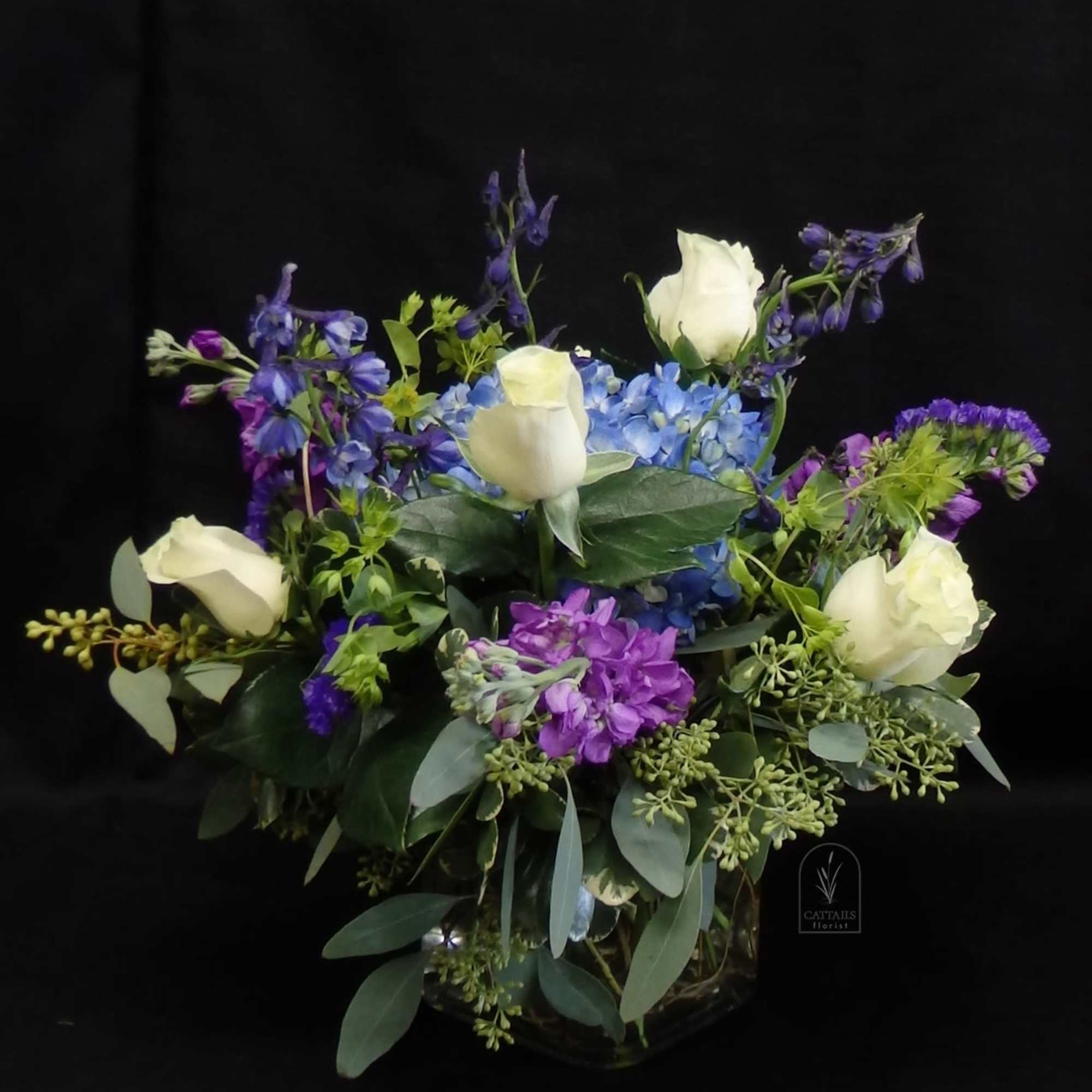 Graceful and soothing, "Cool Comfort" blends soft white roses, vibrant blue delphinium