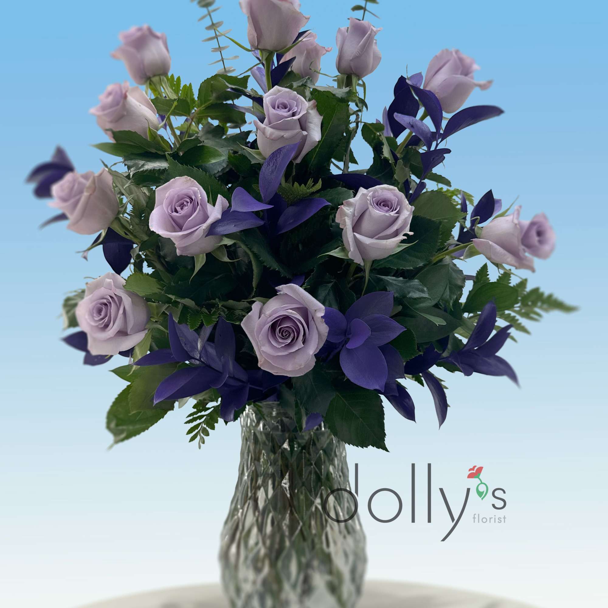 Lavender roses and dark purple flowers in a clear glass vase