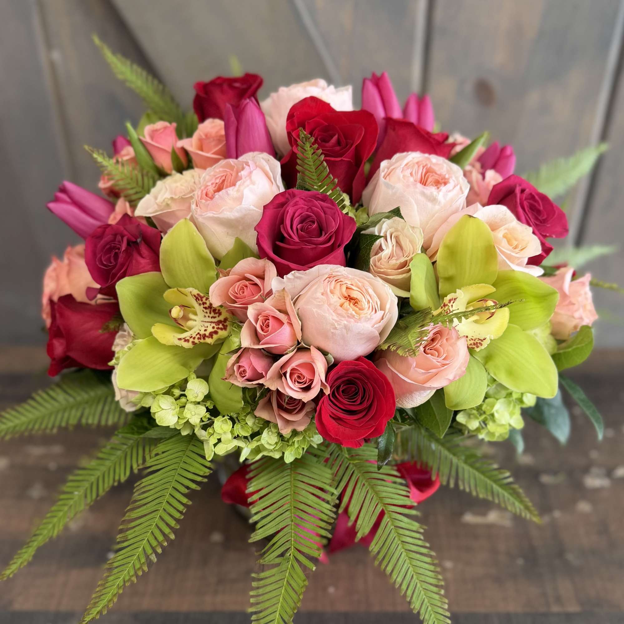 Bouquet of pink and red roses with green orchids
