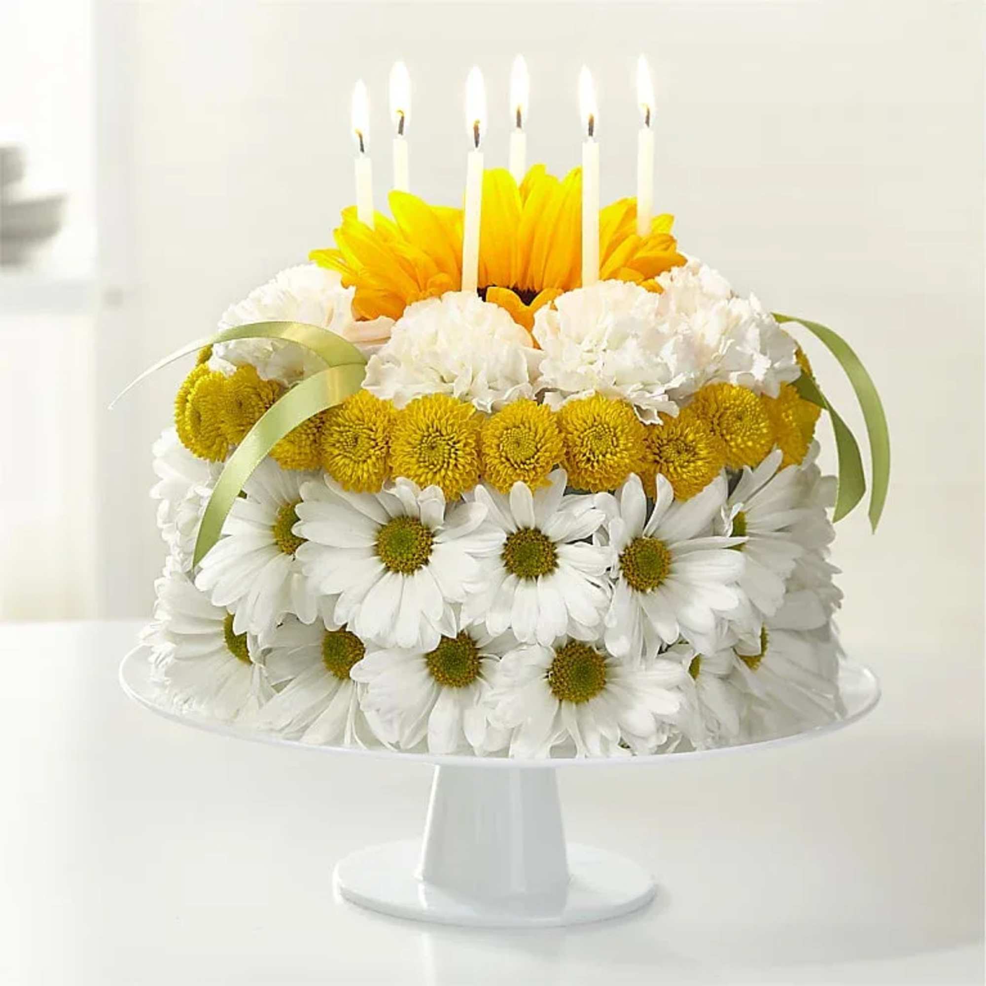 A floral "cake" built from daisies, chrysanthemums, and a single sunflower makes