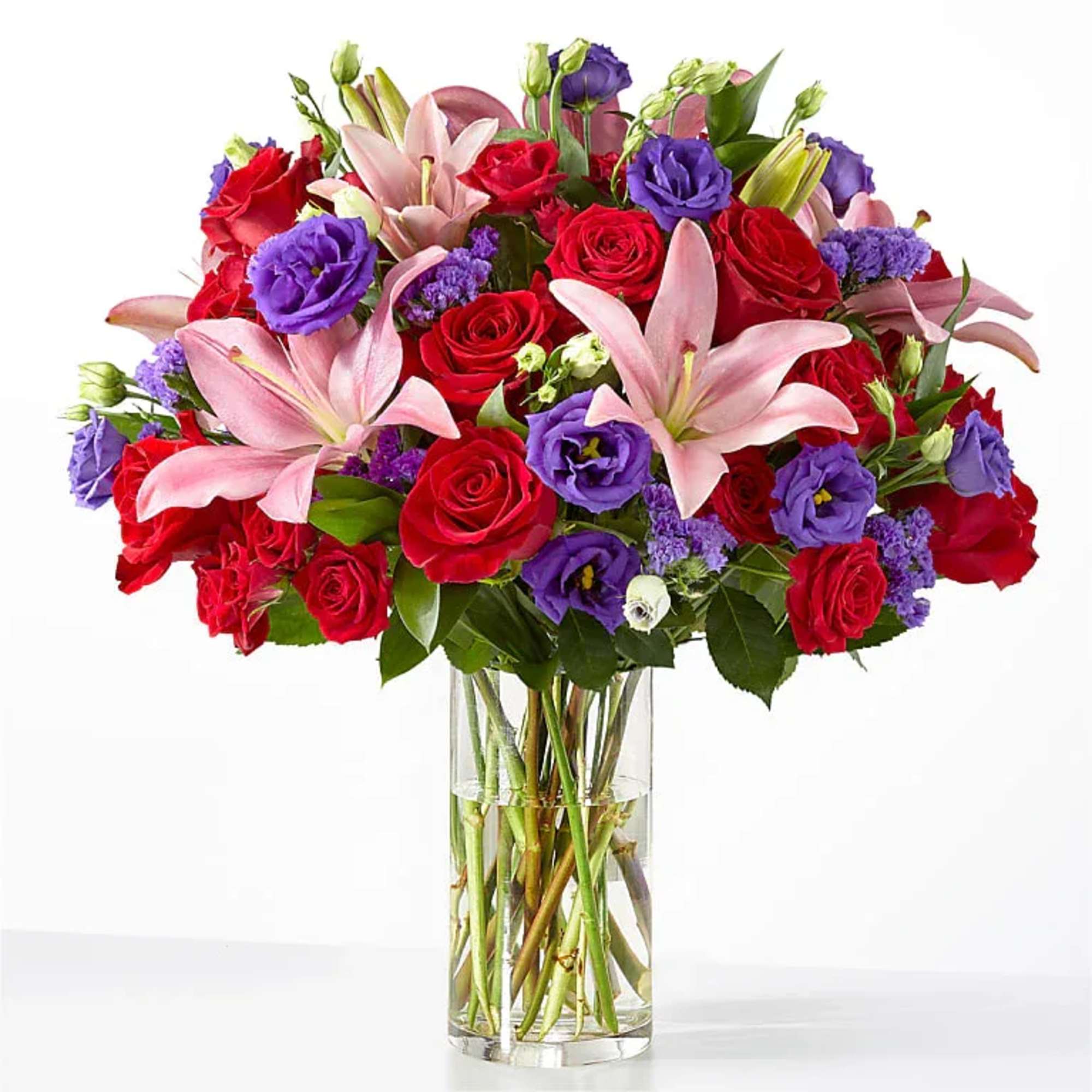 Striking red roses meet soft pink lilies in a full, rounded mixed