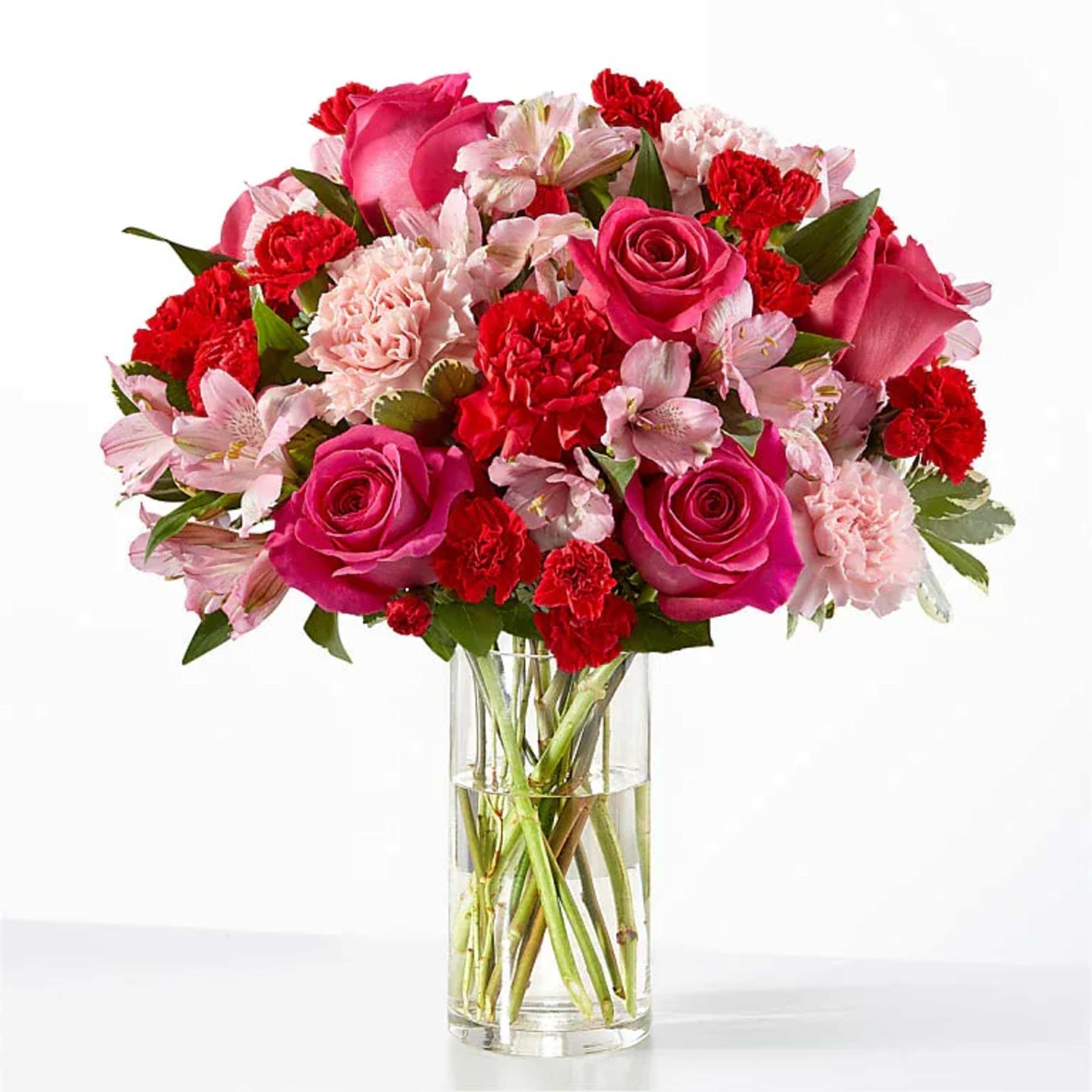 A lush cluster of hot pink roses and vivid red carnations, softened