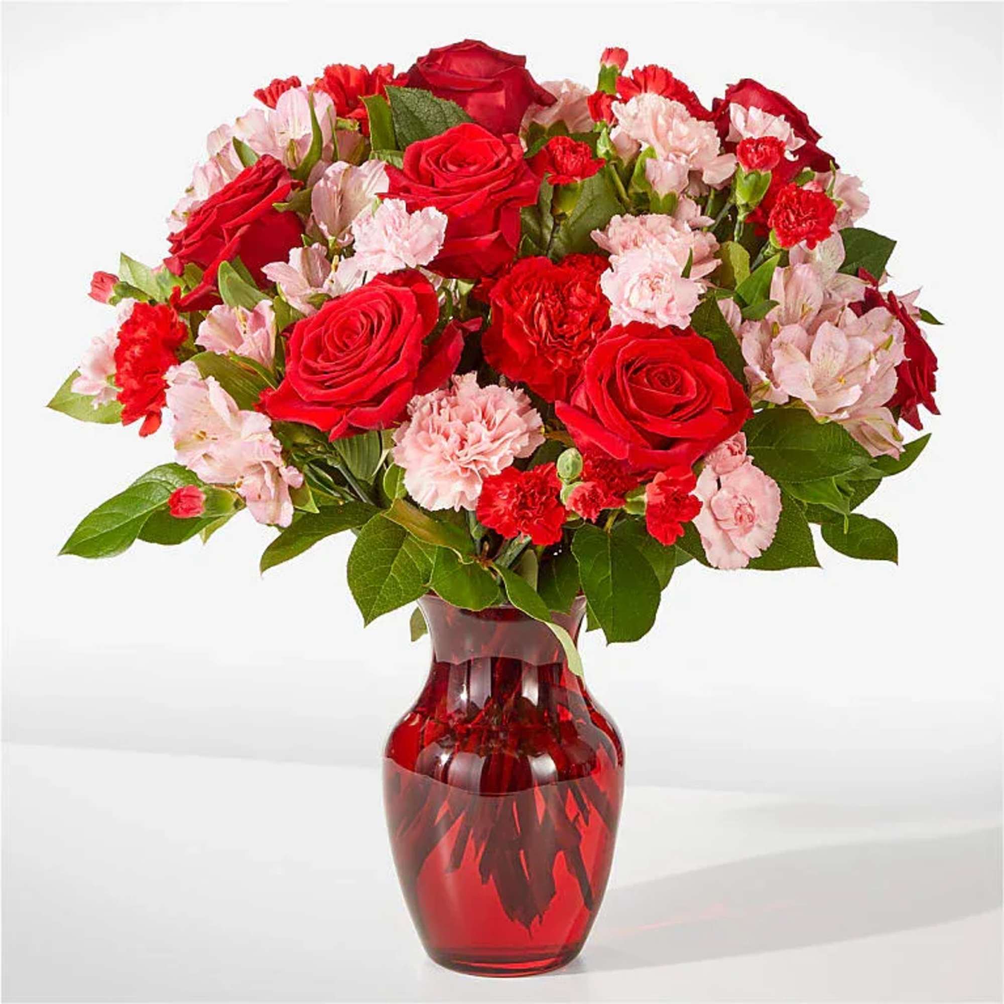 A lush cluster of red roses and pink carnations gathered tight in