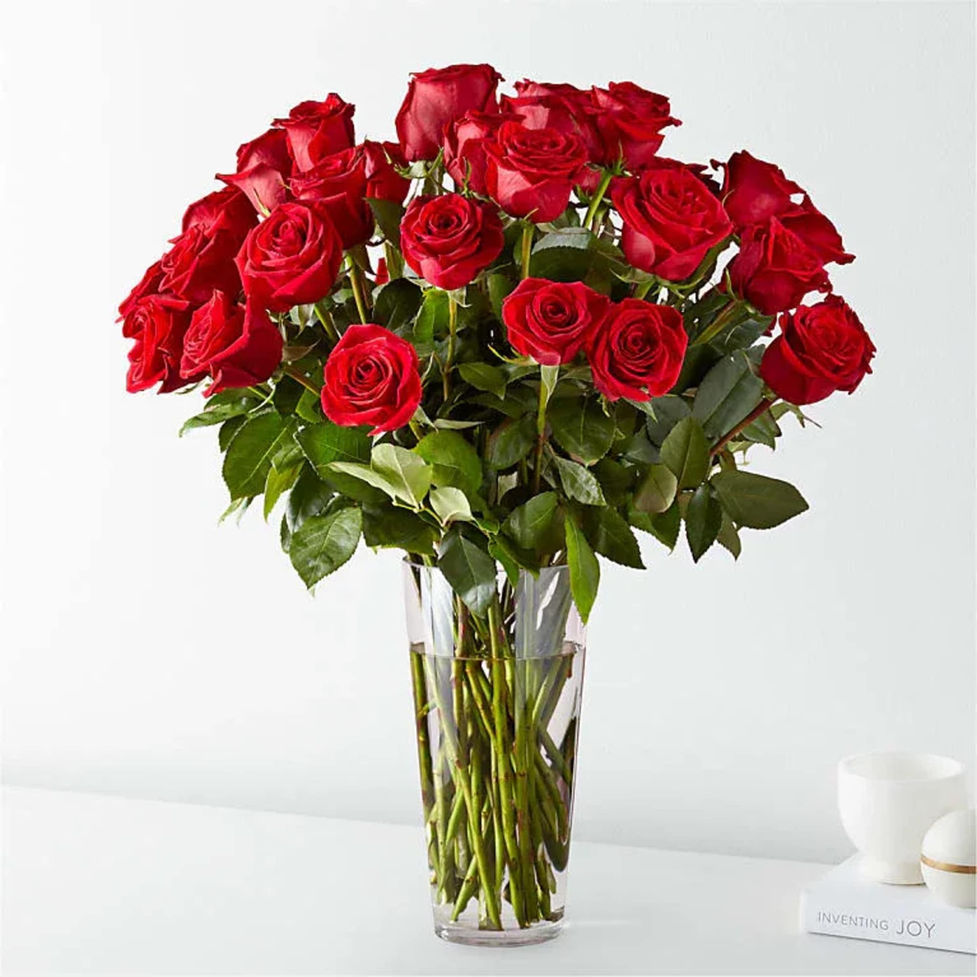 A dozen red roses gathered in a tall clear glass vase creates