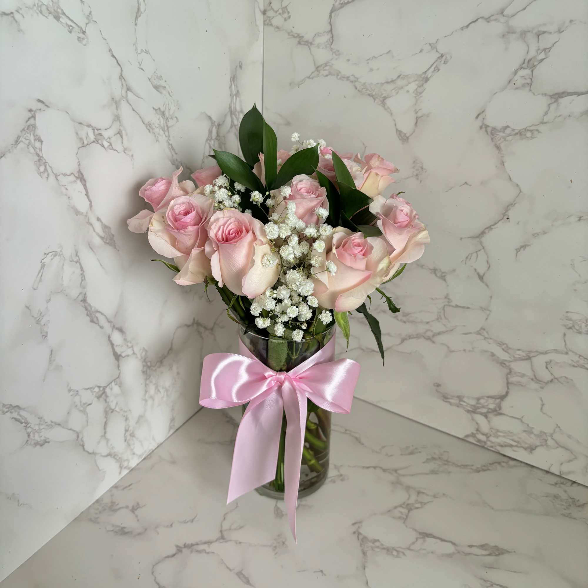Pink roses in a glass vase with a pink ribbon