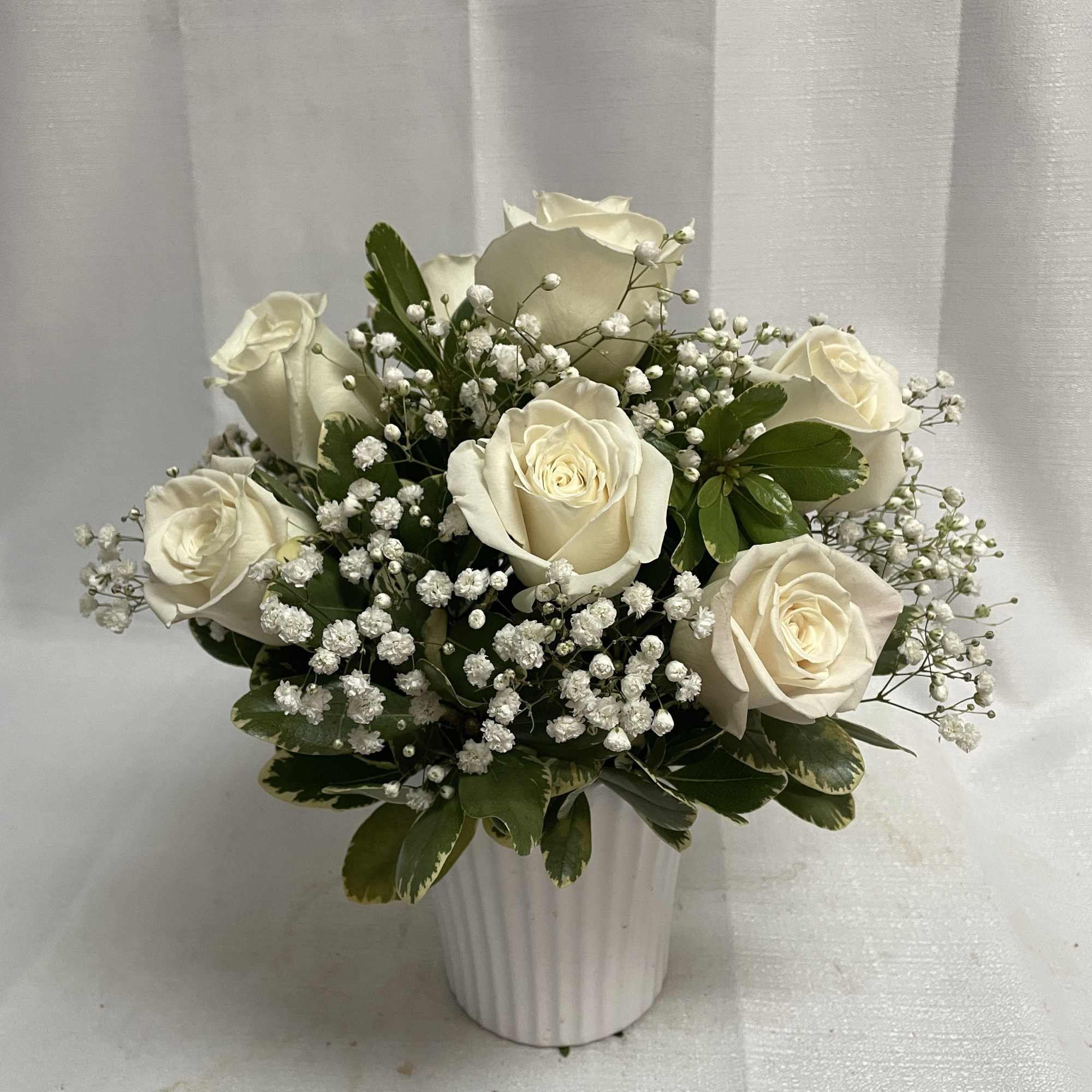 White roses and baby's breath in a white vase