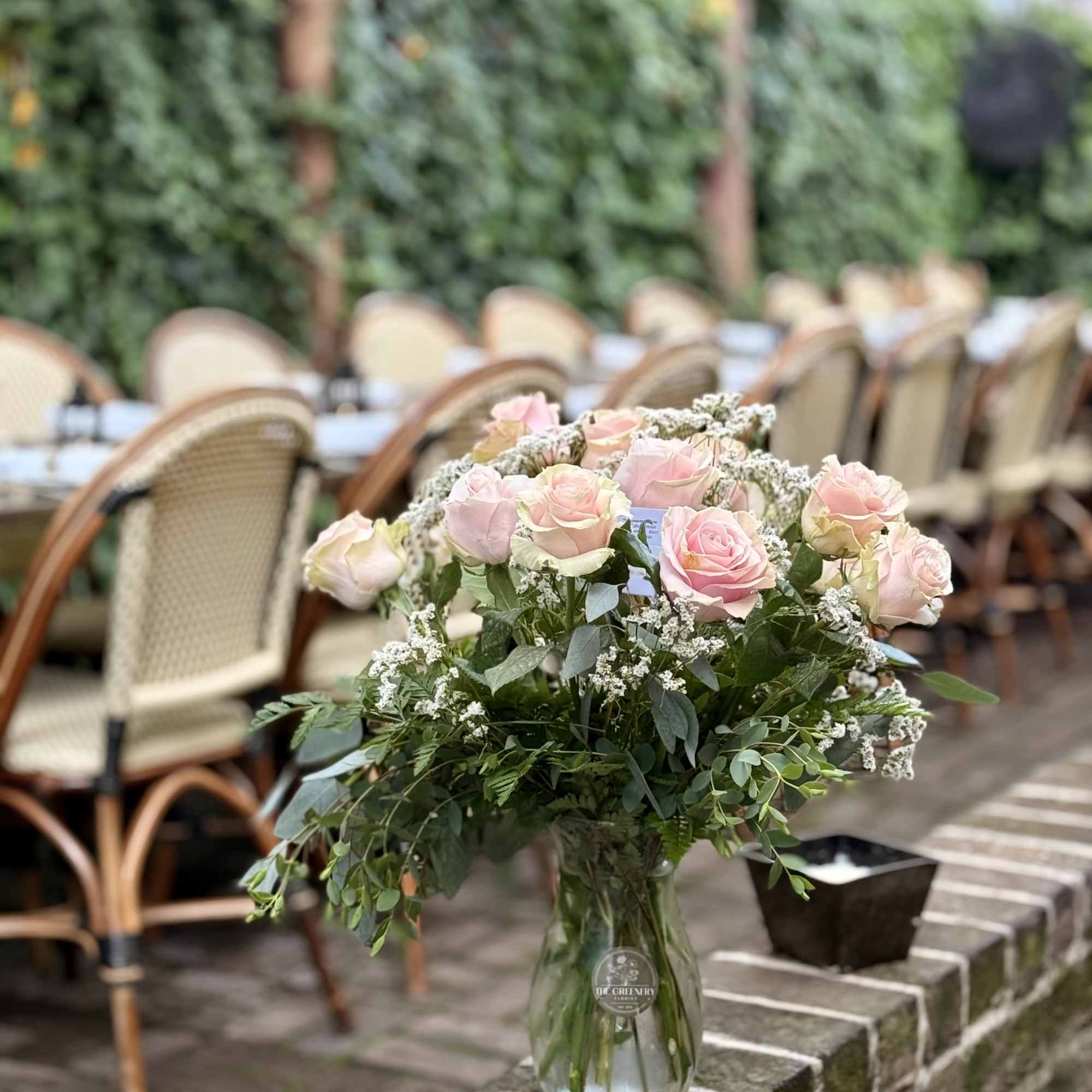 This classic arrangement features a dozen light pink roses accented with fresh