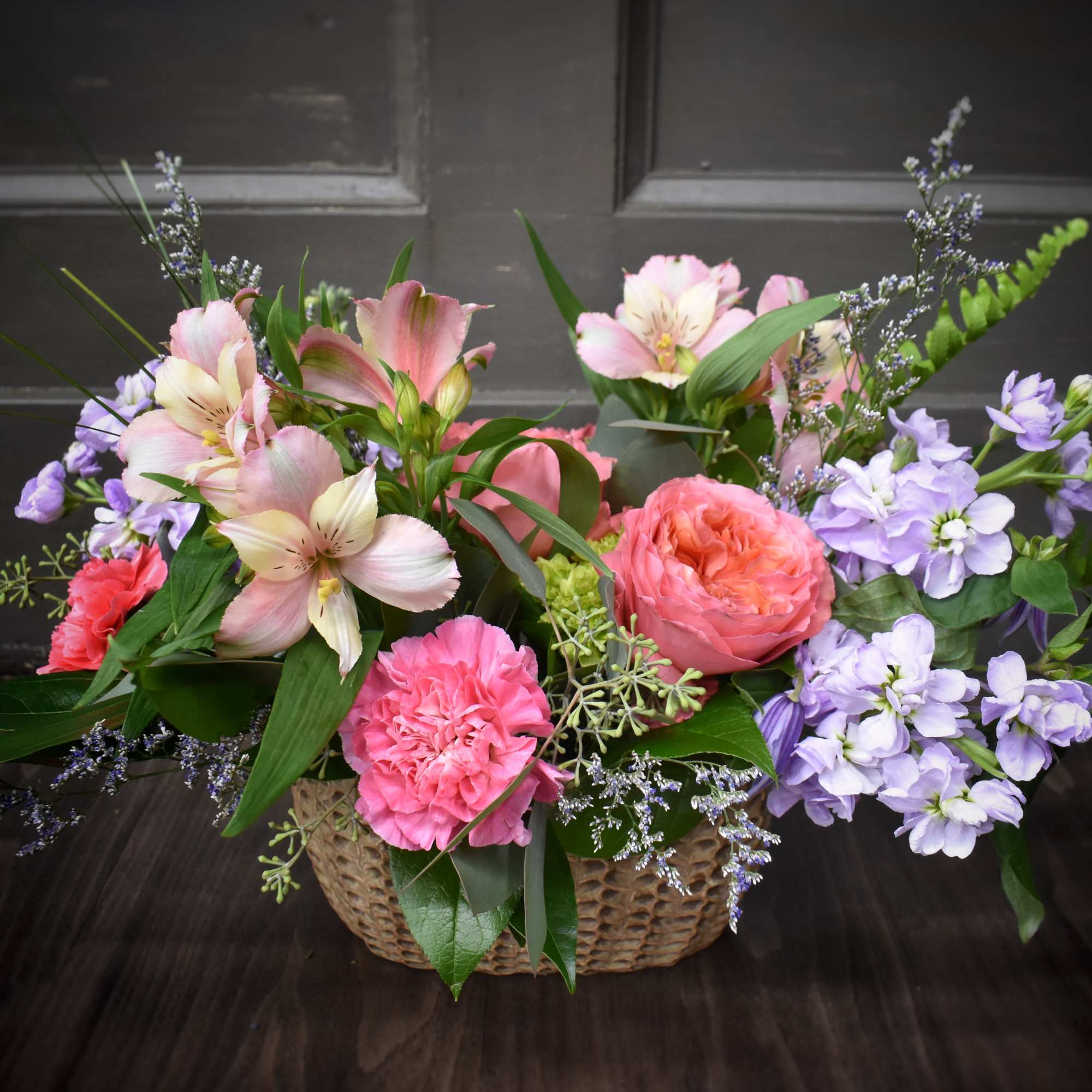 Basket arrangement of pink and lavender flowers with a coral rose