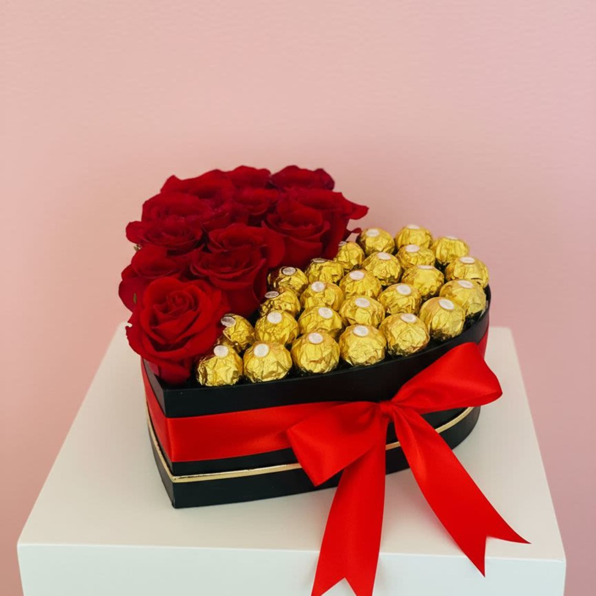 Heart-shaped box with red roses and gold-wrapped chocolates tied with a red ribbon