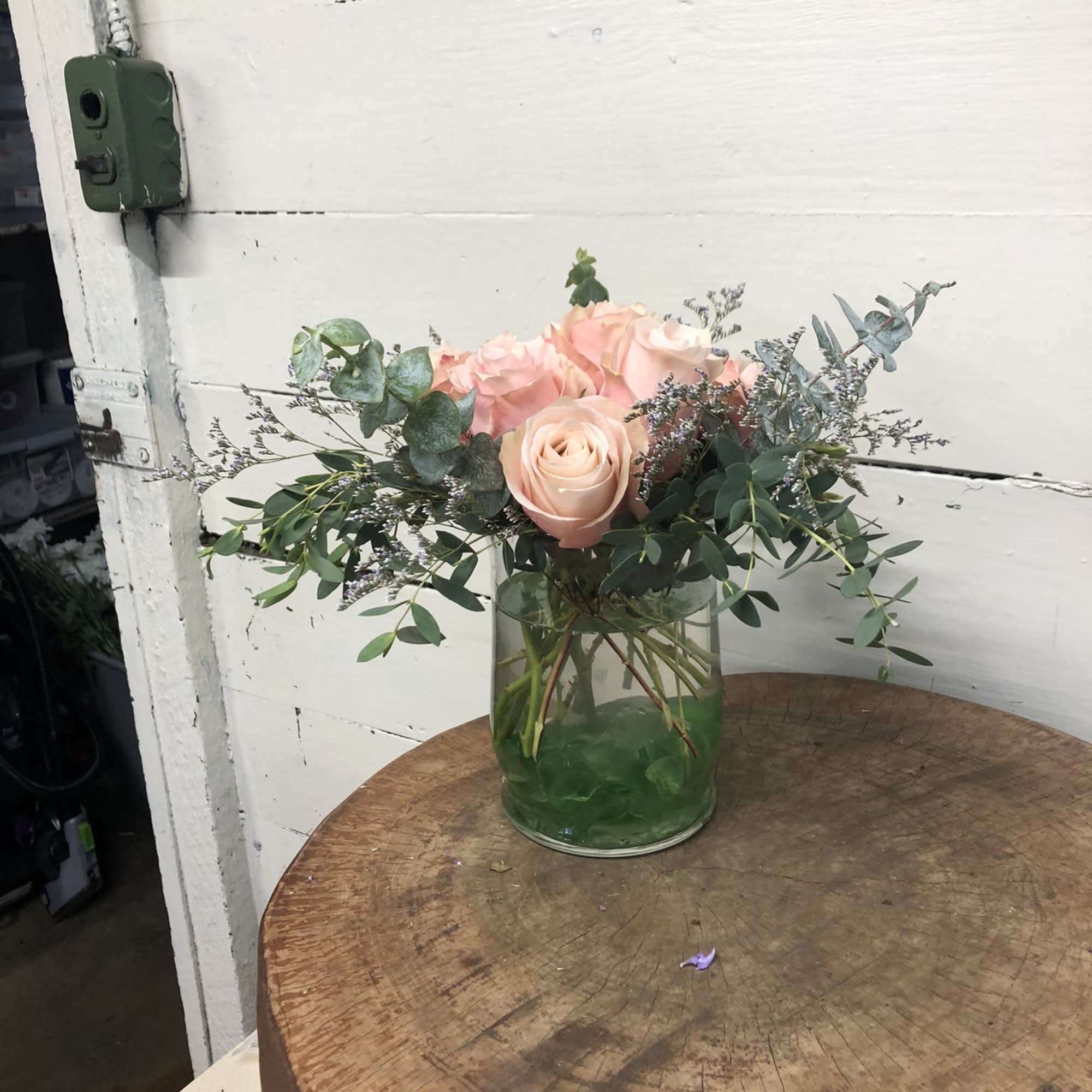 Blush roses in a clear glass vase with airy greenery