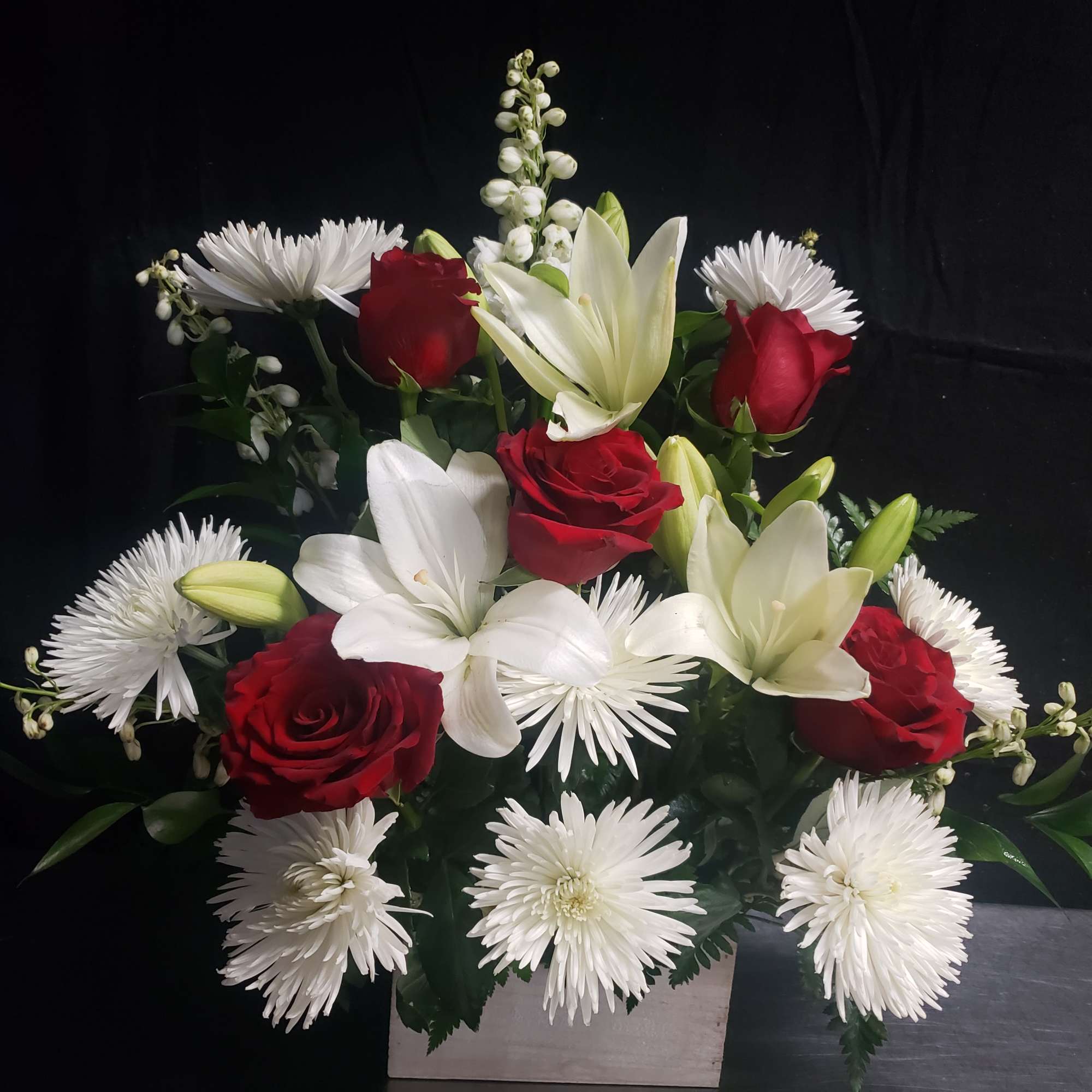 Deep red roses set against crisp white lilies and daisy-like blooms create