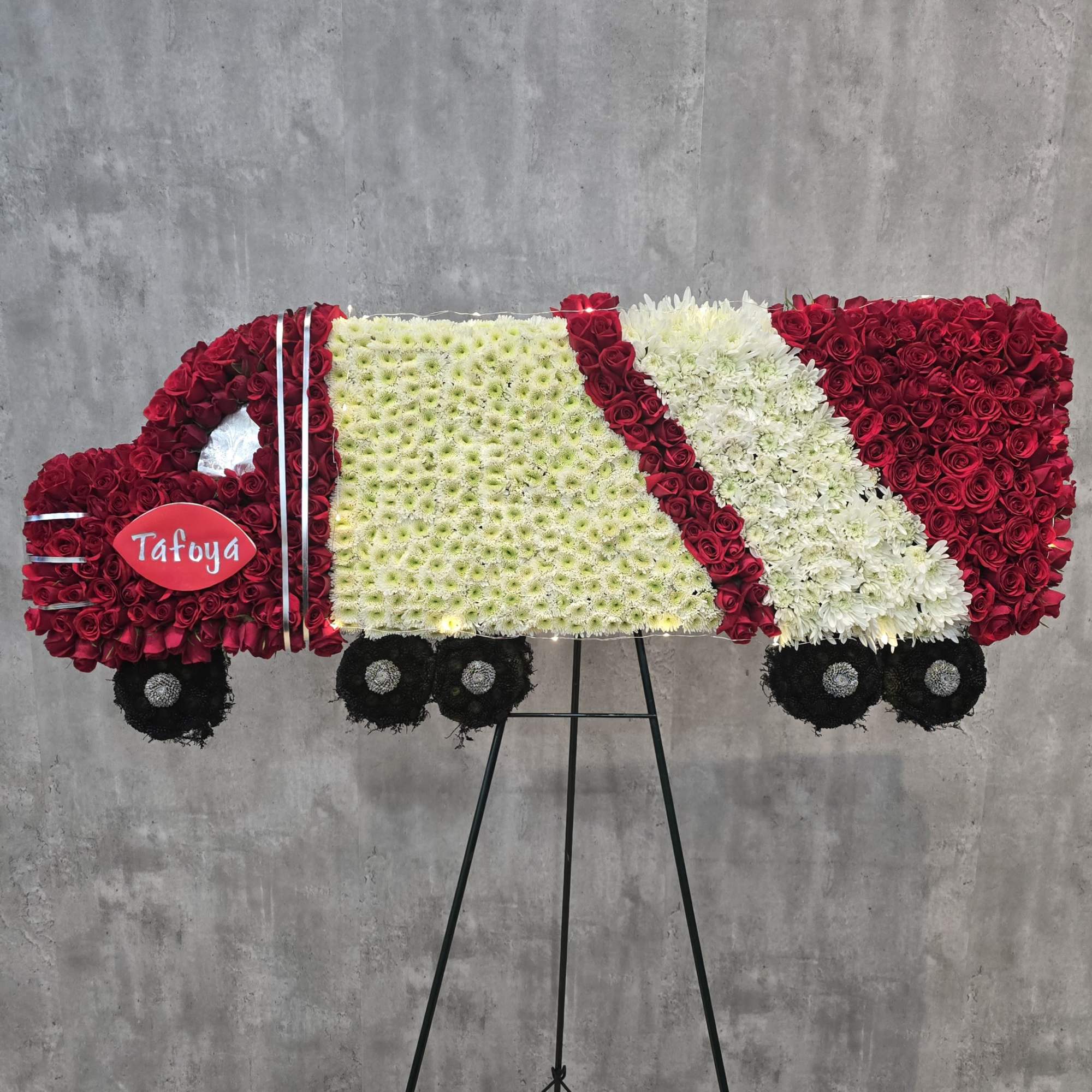 A handcrafted semi truck tribute covered in white chrysanthemums with red accents