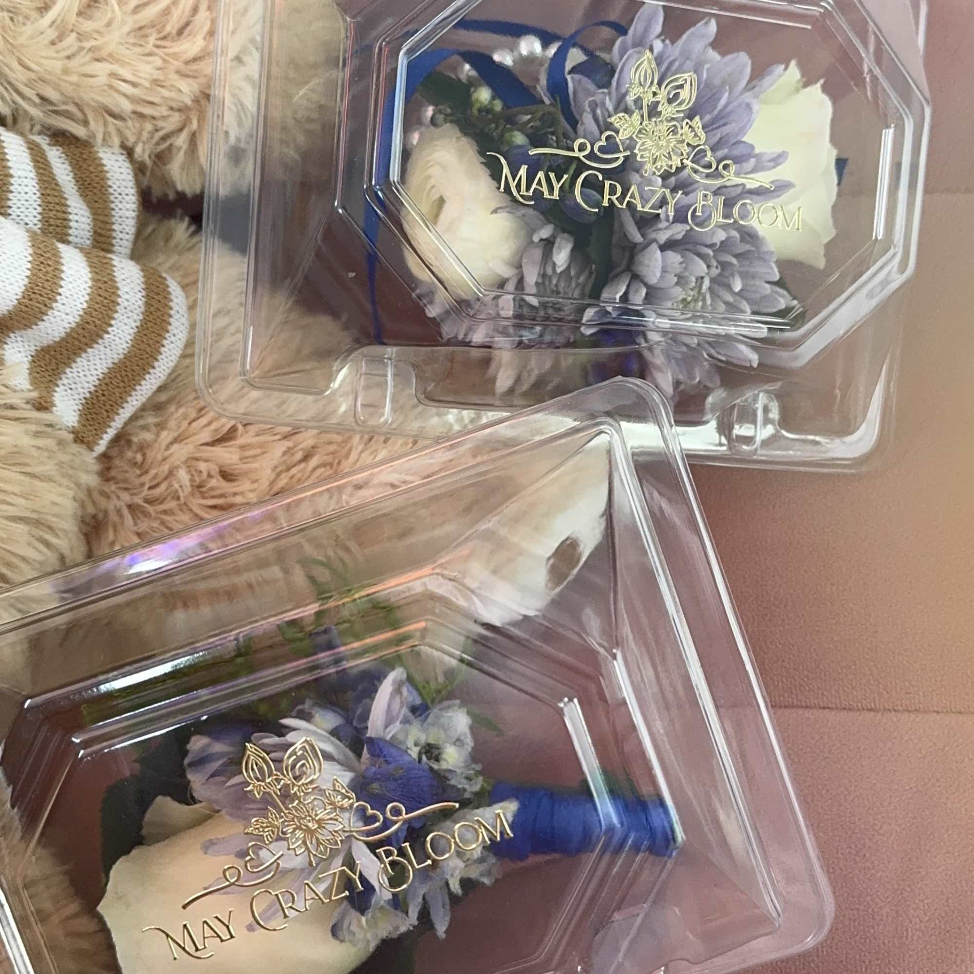 Two small boxed floral boutonnieres with cream and lavender flowers