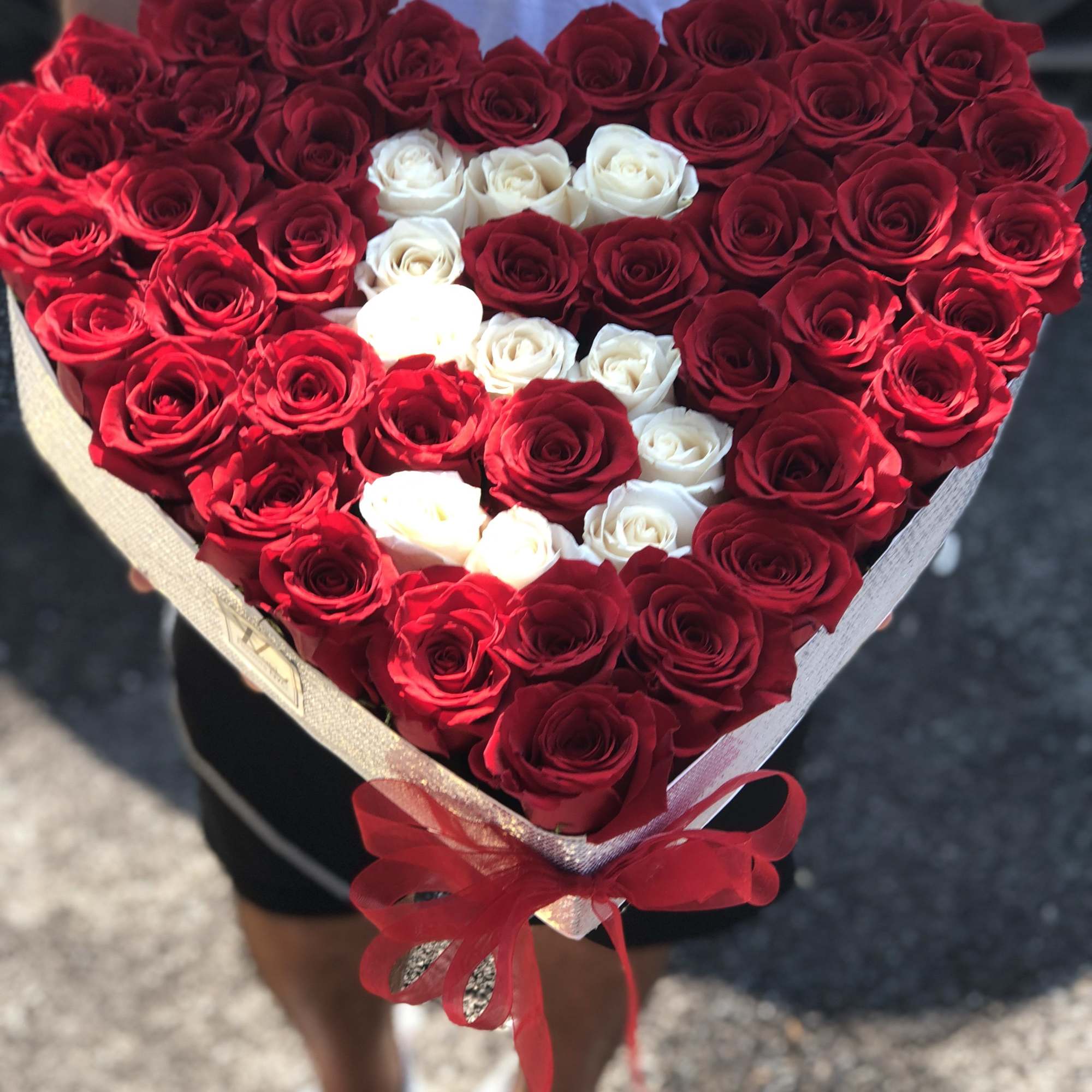 Heart-shaped bouquet of red and white roses tied with a red ribbon