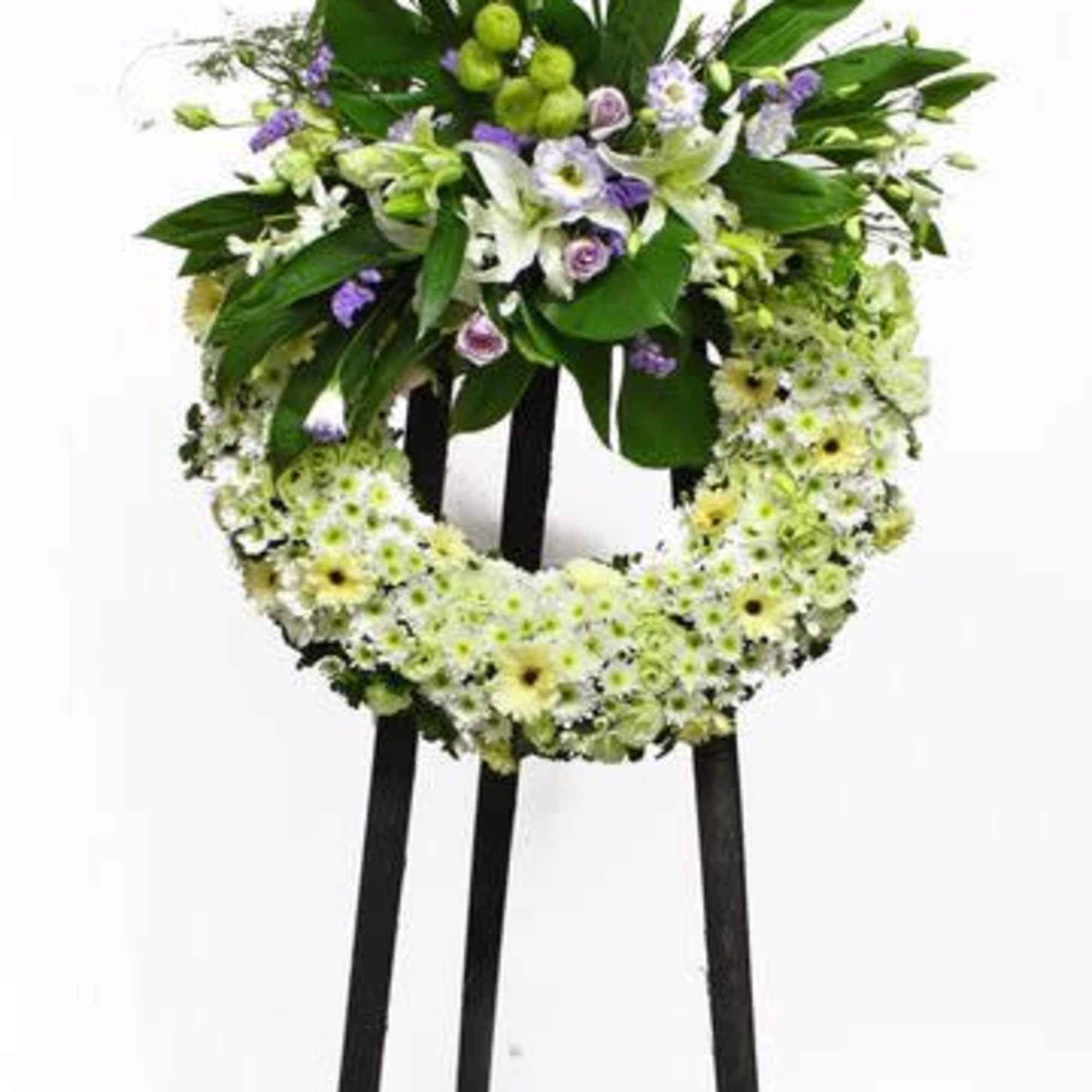 Standing floral wreath with white and pale green flowers on a black easel