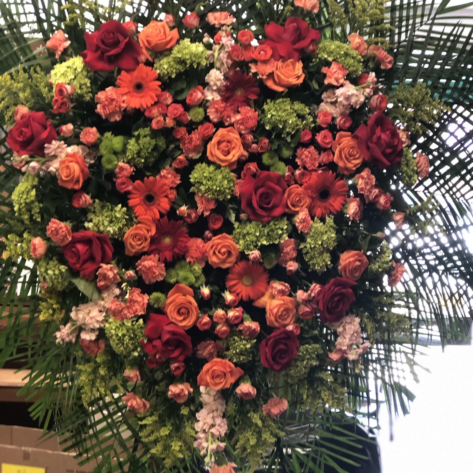 Large heart-shaped floral arrangement with red and orange roses and gerbera daisies